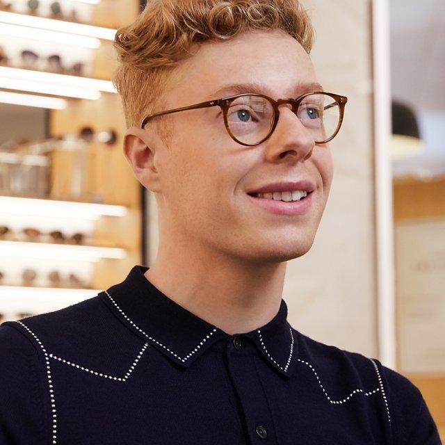 man standing in an opticians wearing glasses