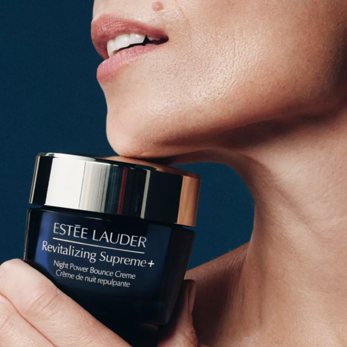 close up of woman holding an Estee Lauder revitalizing creme under her chin