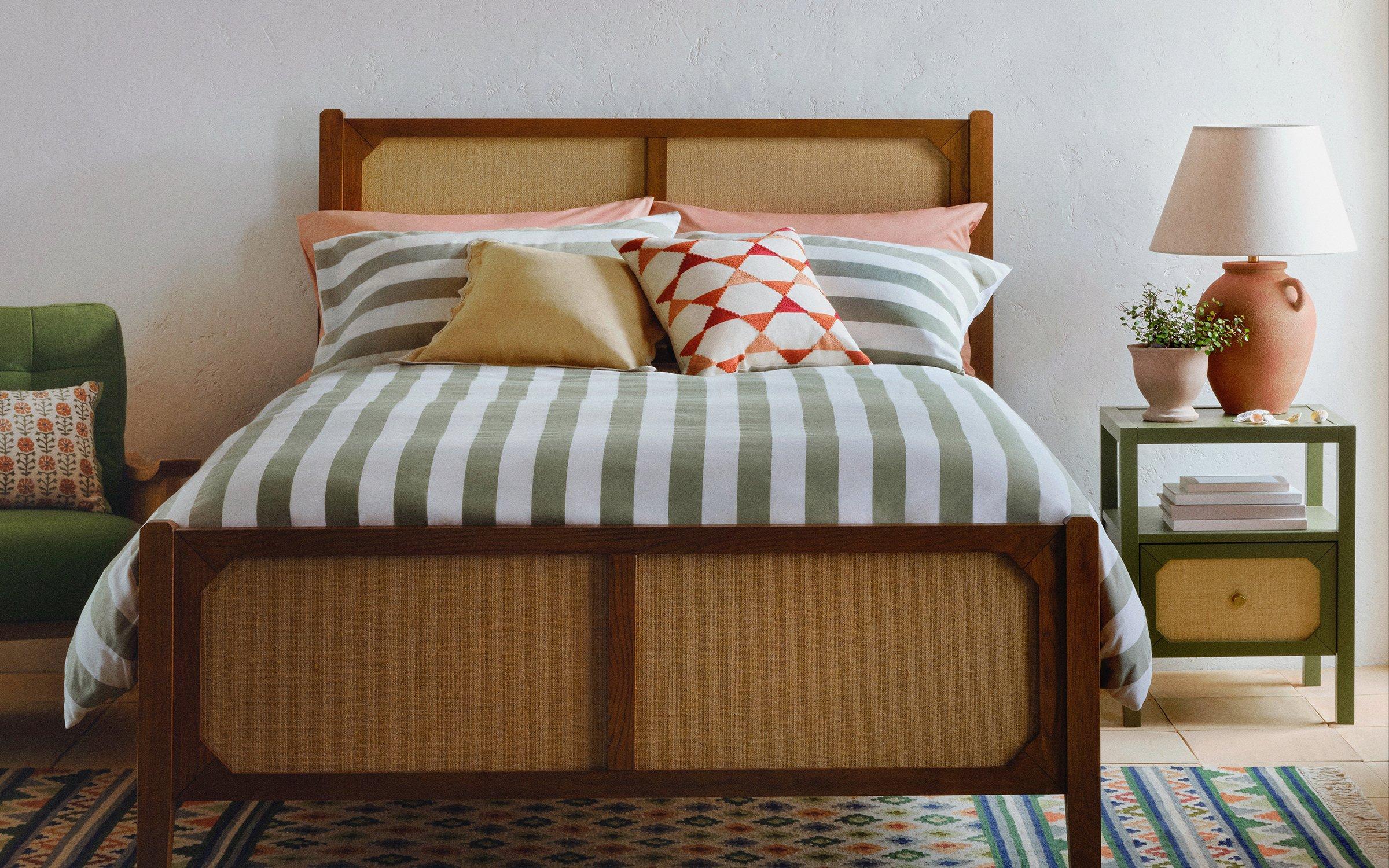 Bedroom with wooden bedframe, green and white striped bedding and green and terracota accessories