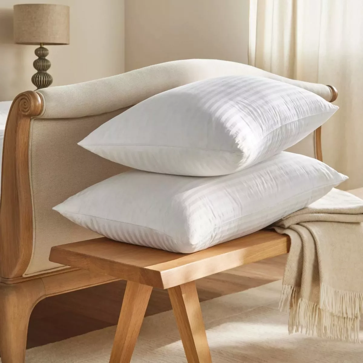 Modern bedroom with a striped bed, wooden furniture, and large window overlooking greenery, creating a serene atmosphere.