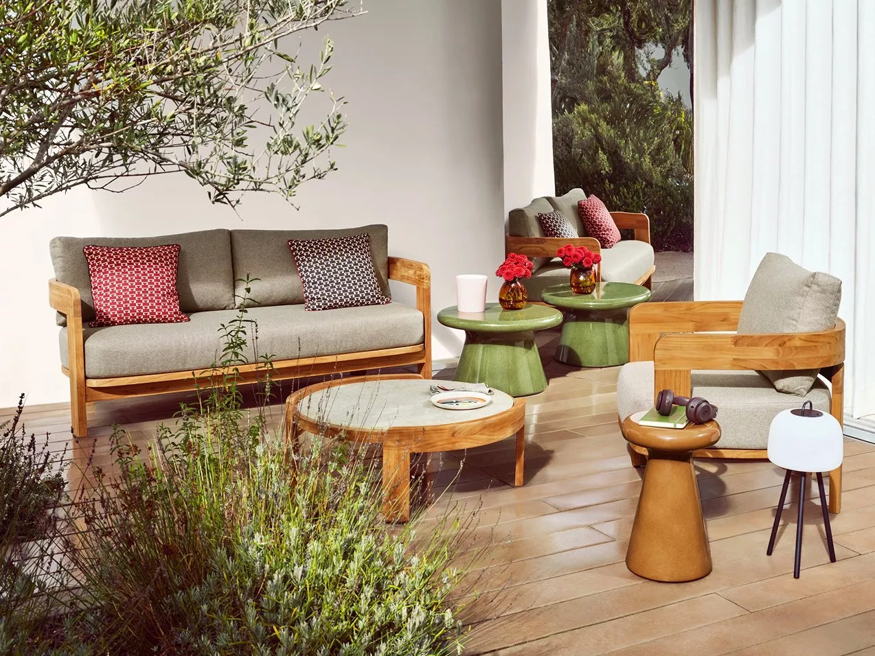 Modern outdoor patio seating with wooden sofas, grey cushions, green side tables.