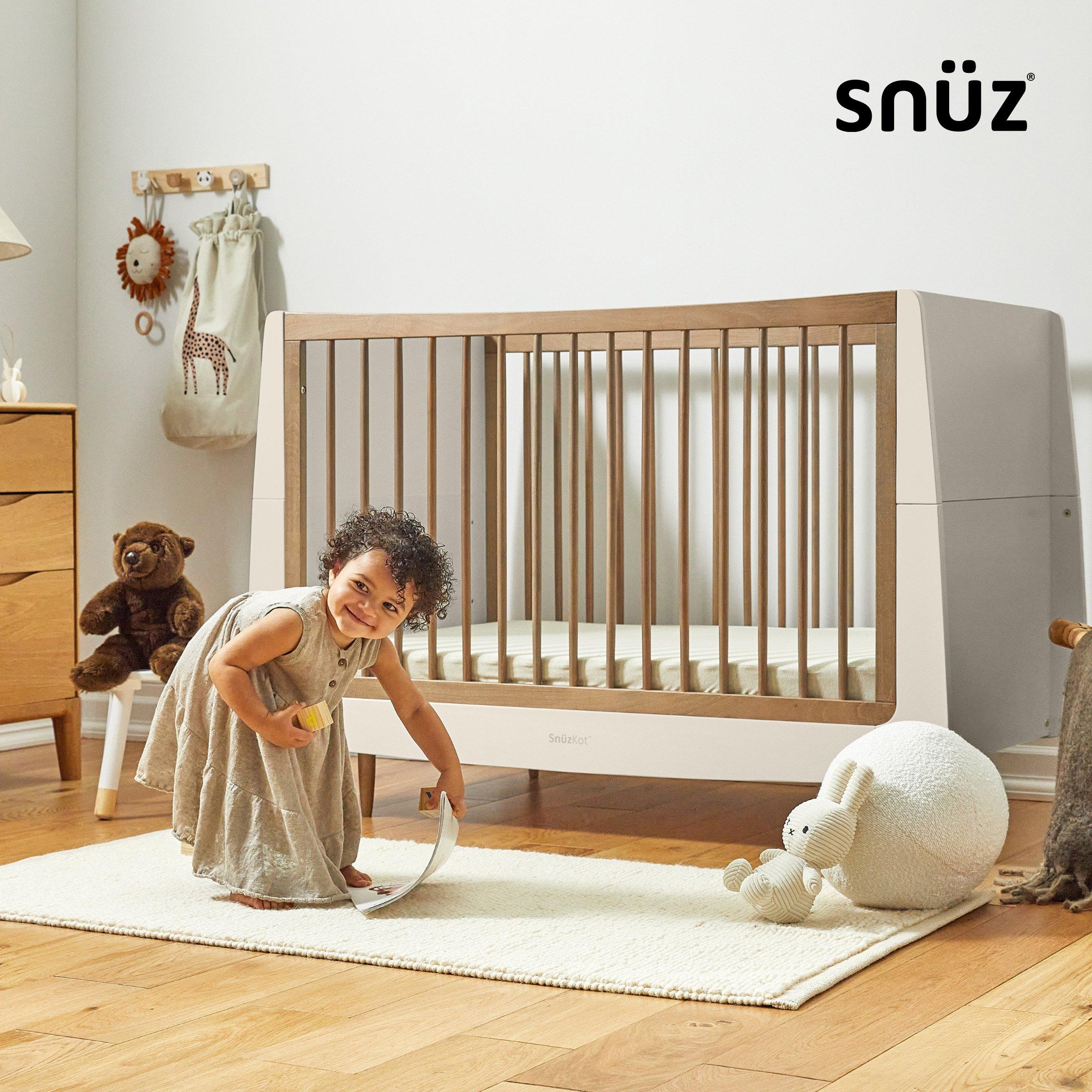 snuz nursery furniture baby girl picking book on mat near kot, teddy bear, cotton ball with toy