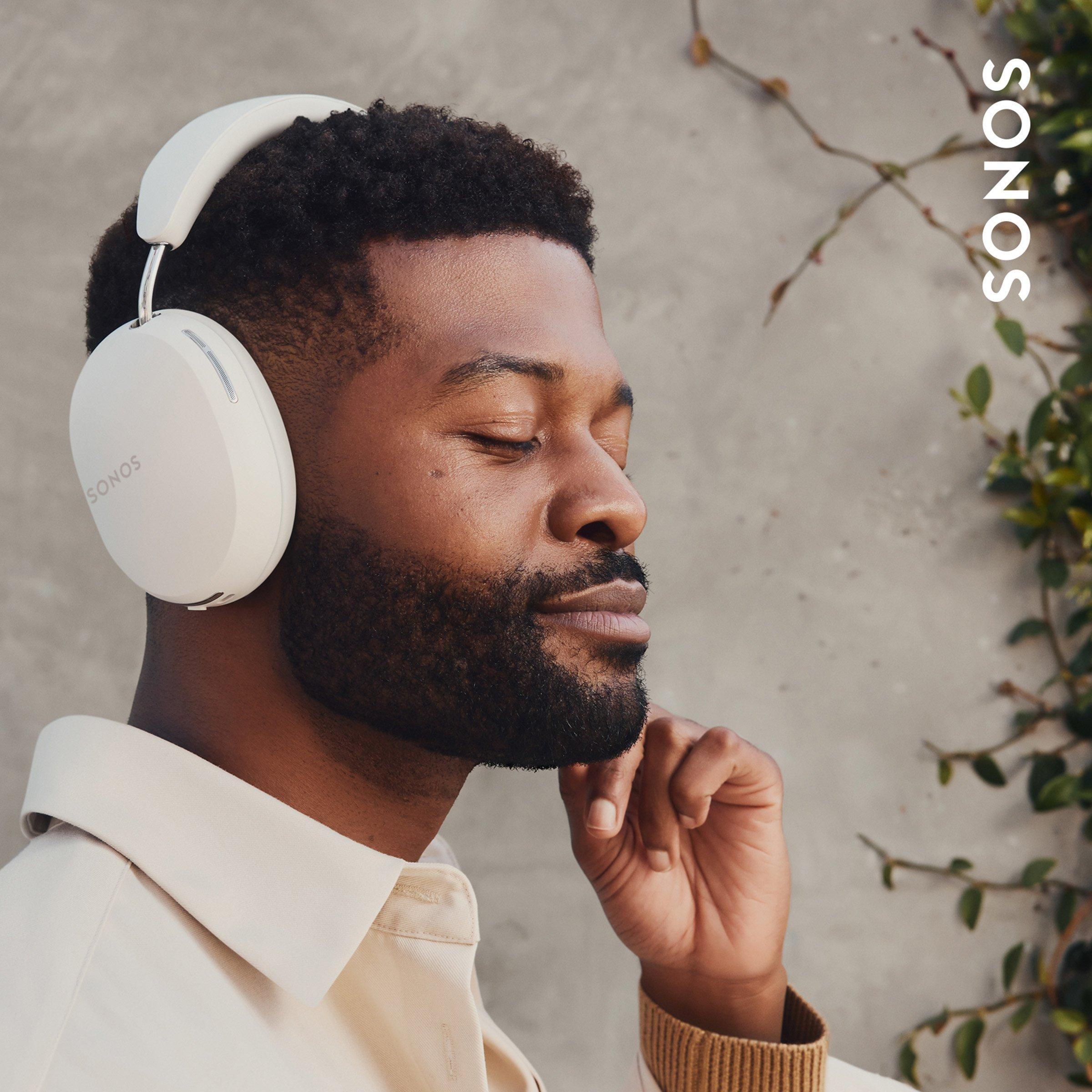 Man wearing white SONOS headphones with eyes closed, relaxing.