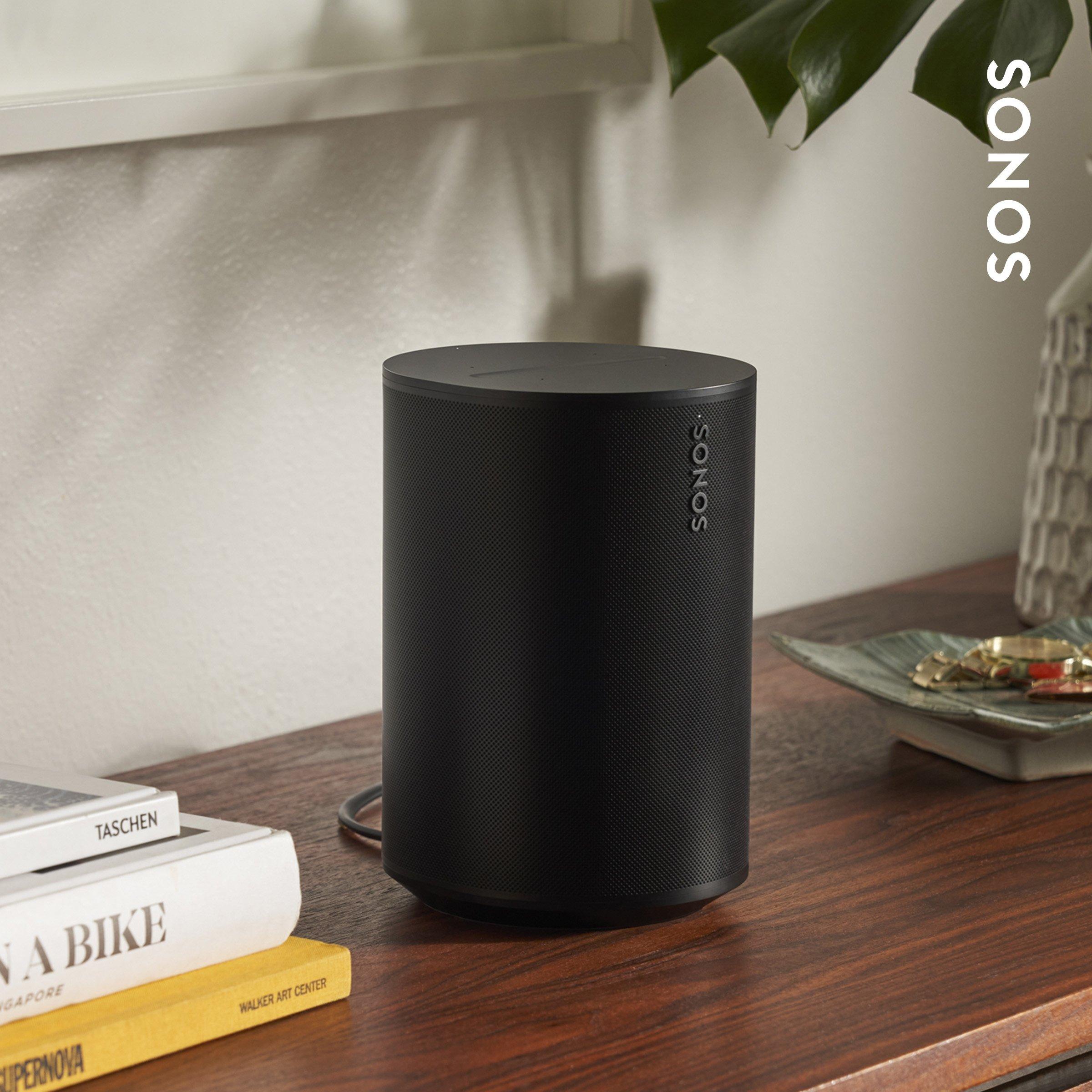 Black SONOS speaker on a wooden surface with books.