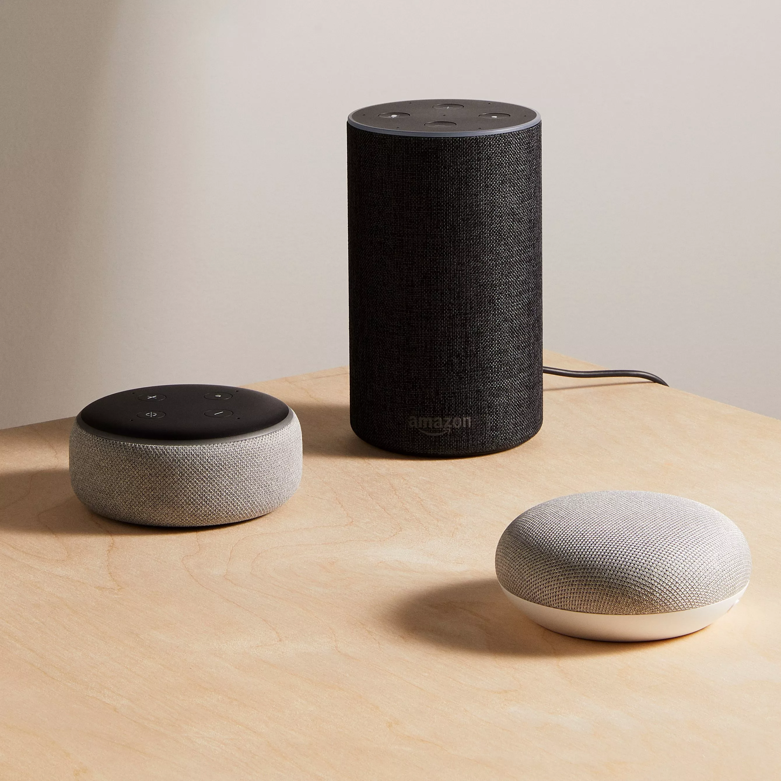 Amazon Echo smart speakers and Google Nest Mini on wooden table, modern voice assistant devices in home setting