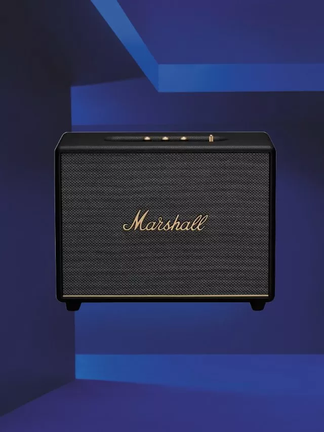 Marshall wireless Bluetooth speaker in black with gold logo, front view on a blue studio background