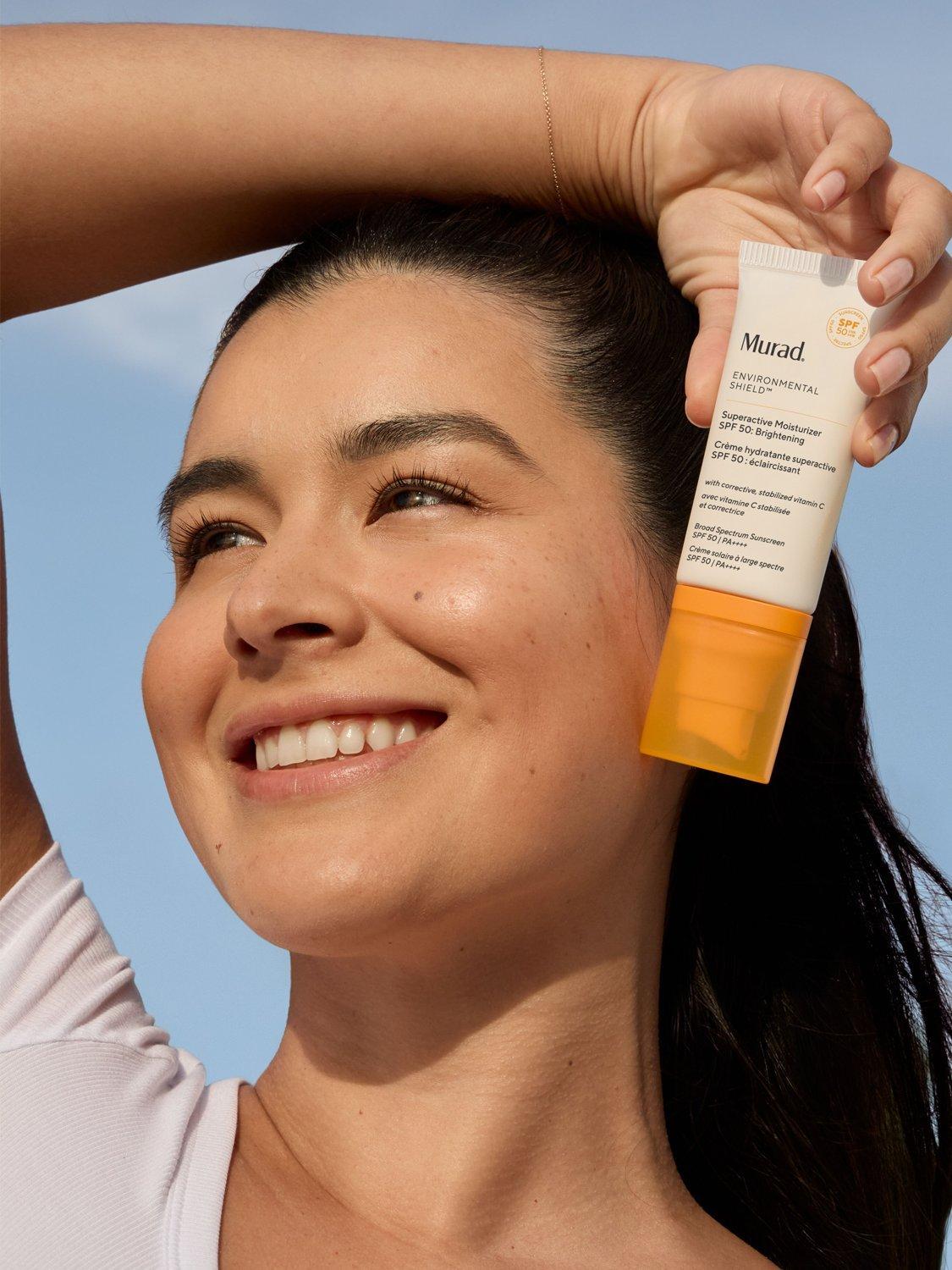 a close up of a lady holding a bottle of Murad over her head