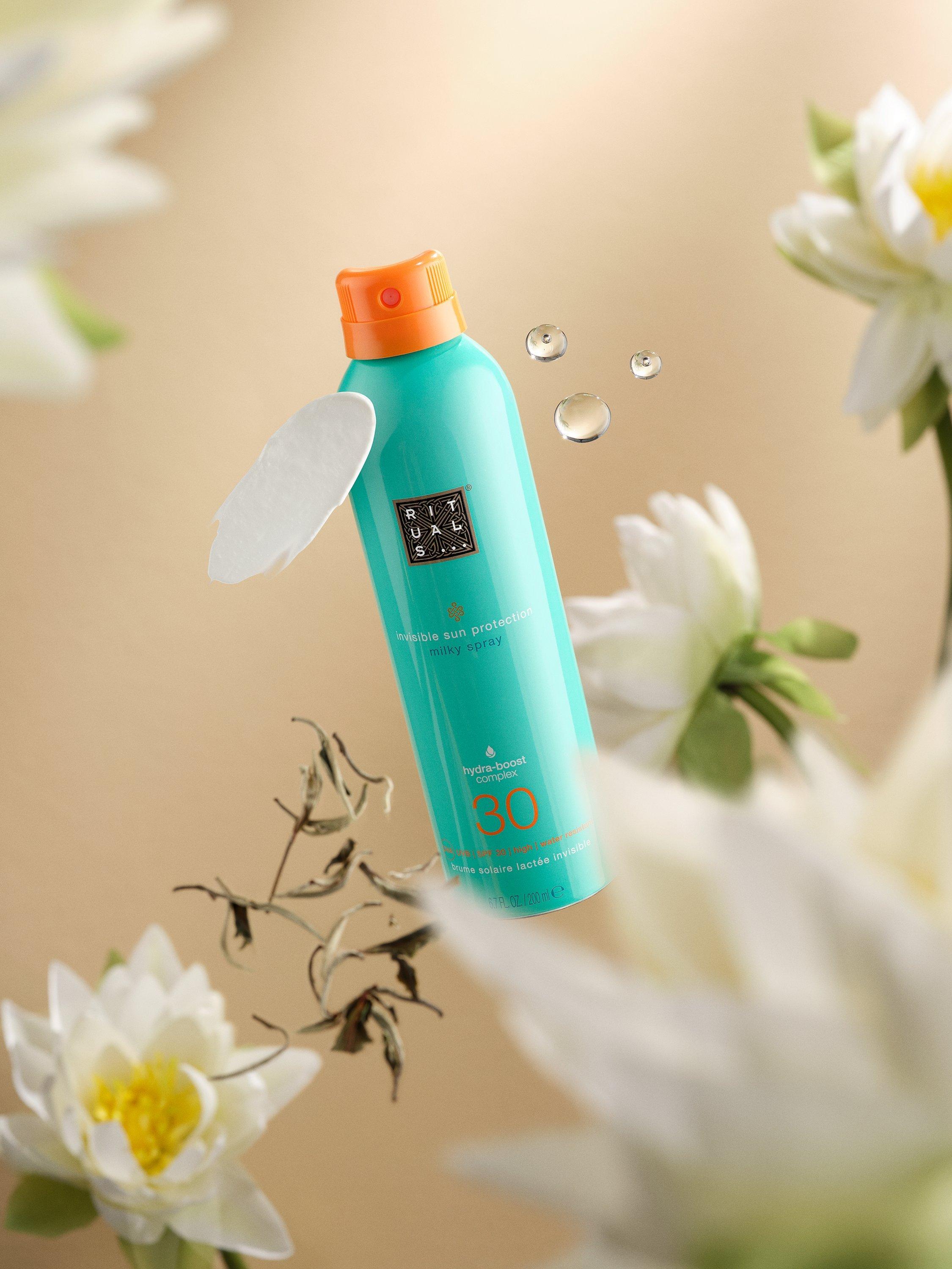 Ritals bottle floating in the air with flowers in the foregorund and background