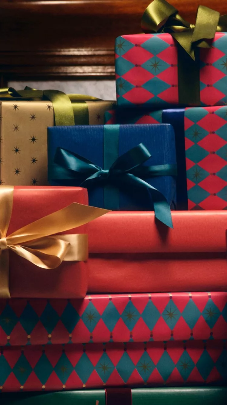 A clear, textured glass vase containing two dark red, possibly chrysanthemum or dahlia-like, flowers.
