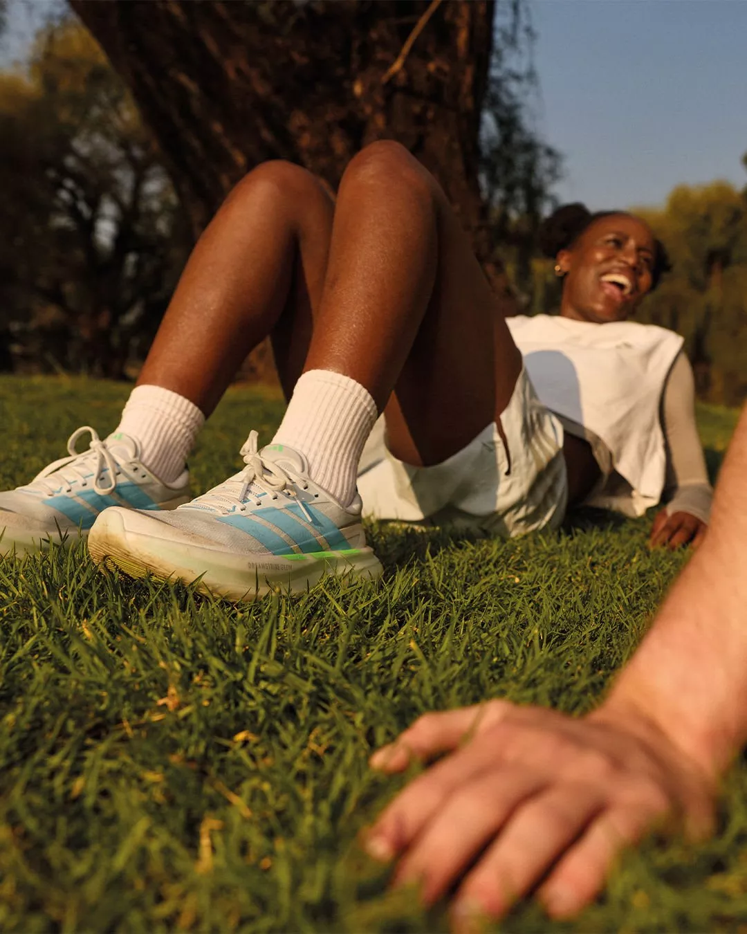 close up of a woman wearing a pair of running shoes whilst lying down on the grass