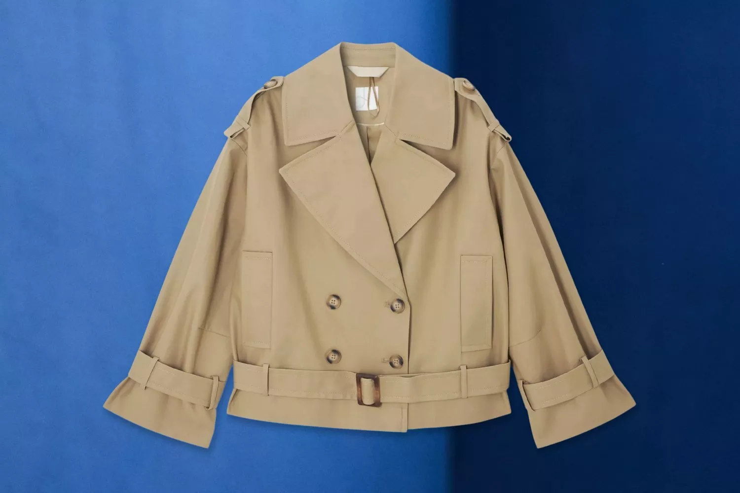 Light blue hooded jacket with drawstrings and front pockets, laid flat on a blue background product photo