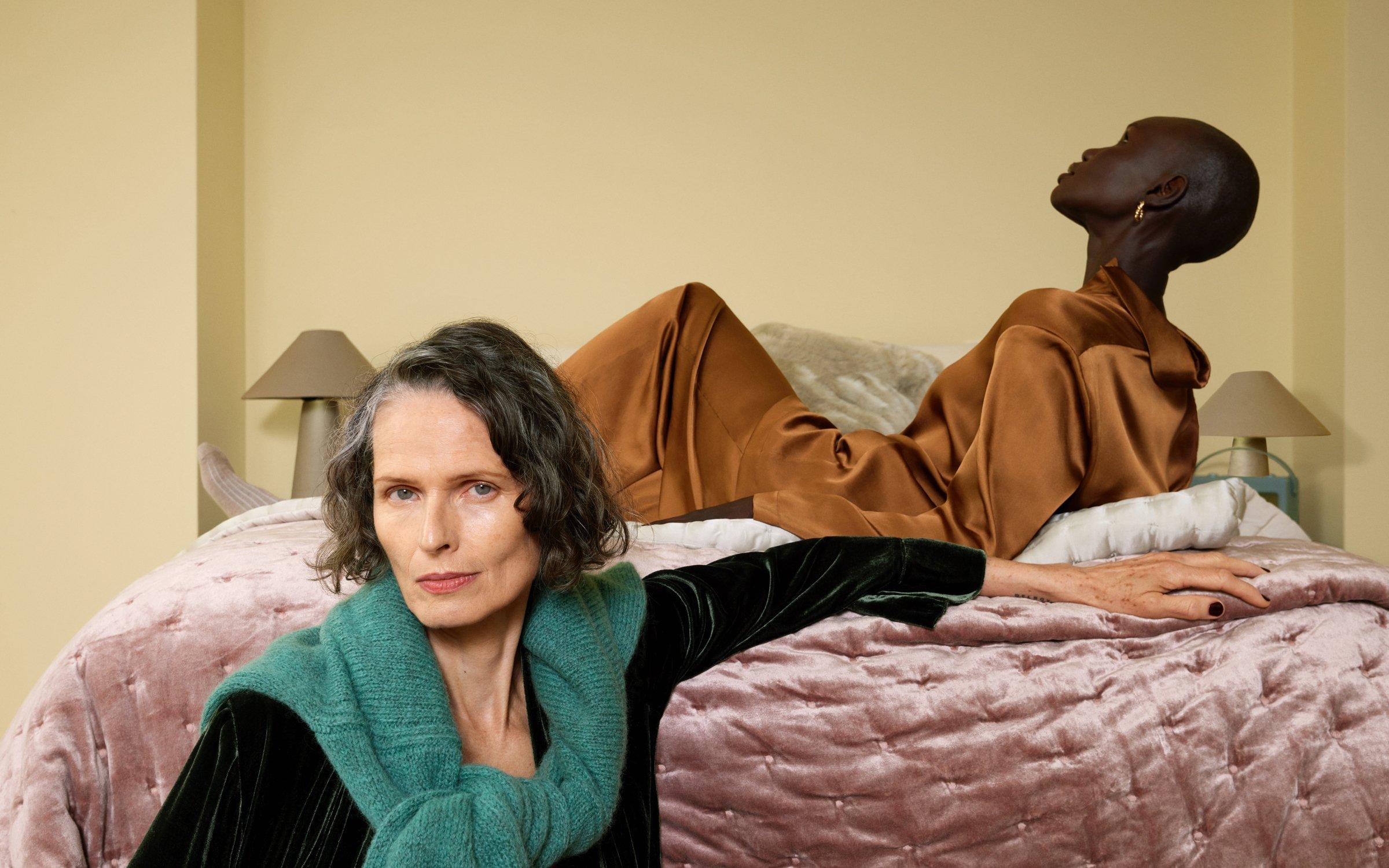 Image of two ladies sitting on and beside a bed