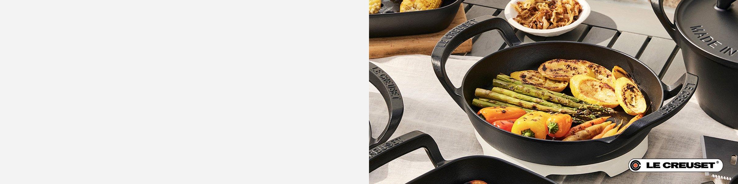 Cast iron Le Creuset pan filled with grilled vegetables on an outdoor dining table