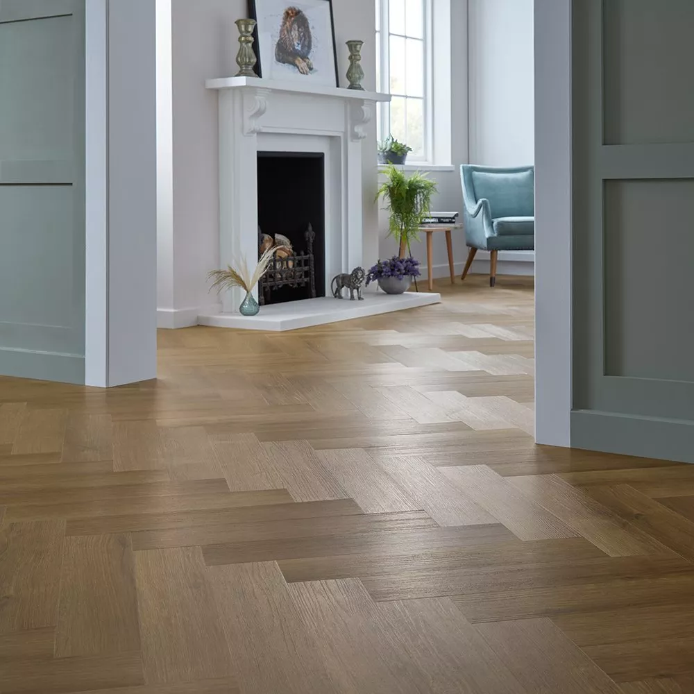 Modern living room with herringbone wood flooring, elegant fireplace, and cosy armchair near window.