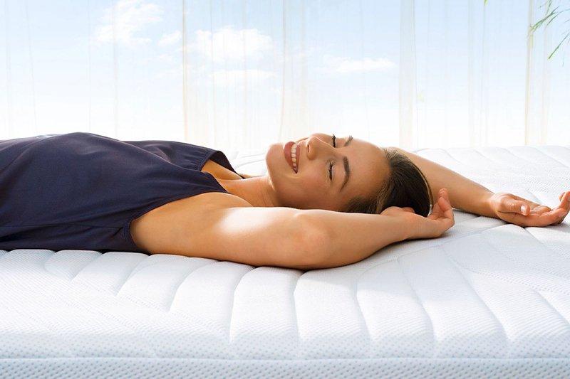 Woman smiling laying on Tempur mattress