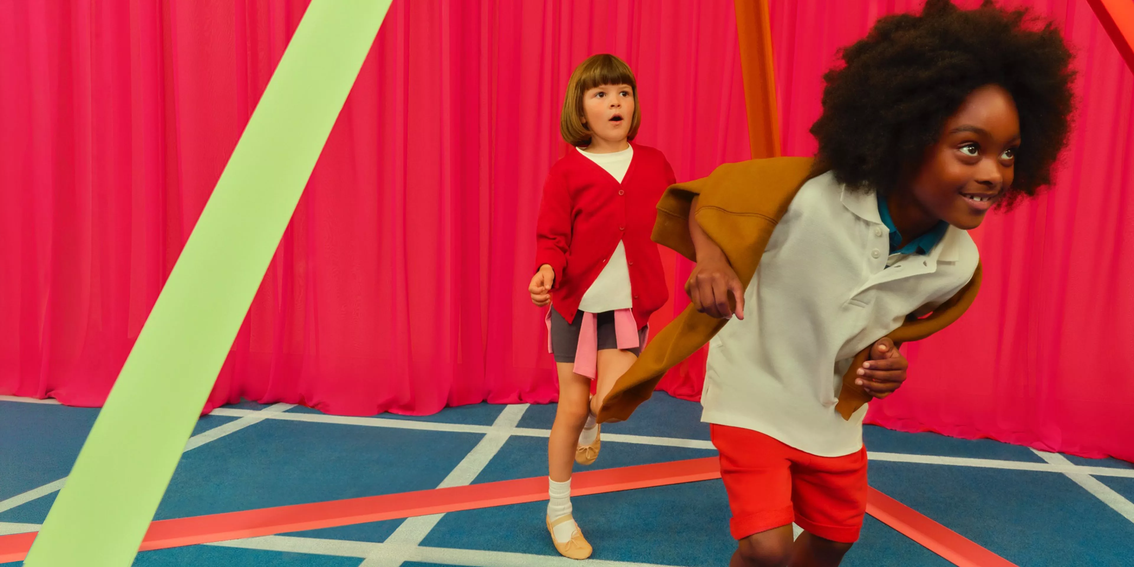 Two children playing in the school gym. Wearing school uniform and sportwear.