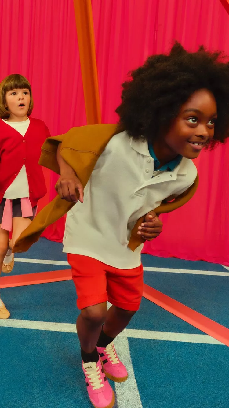 Two children playing in the school gym. Wearing school uniform and sportwear.