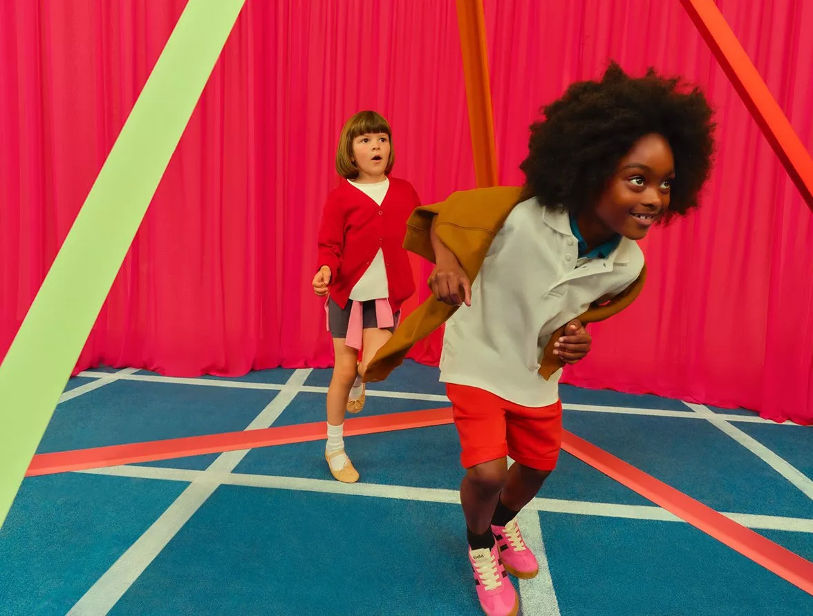 Two kids playing in a school gym wearing school sports wear