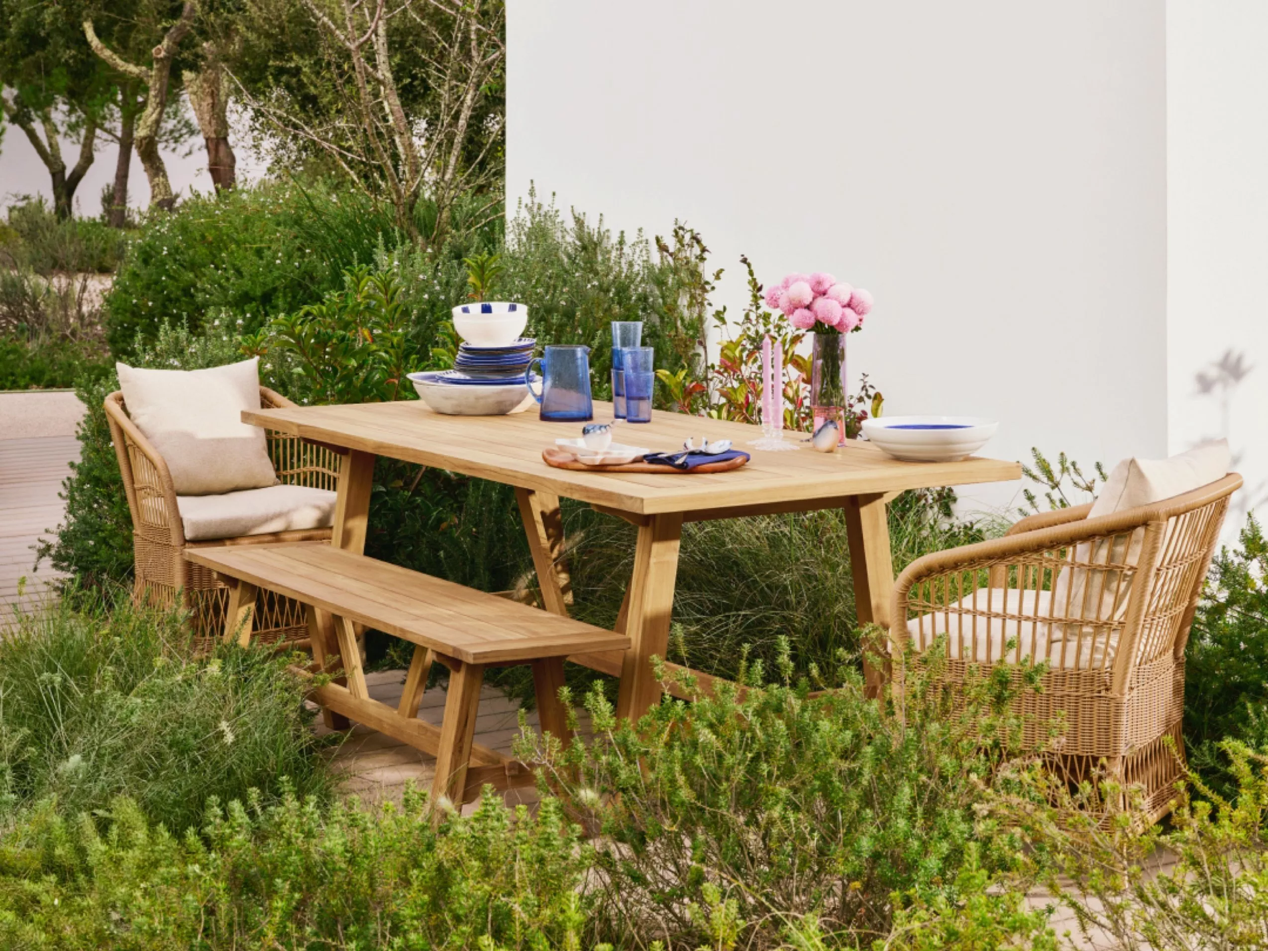 Table and chairs in an outdoor garden setting, displaying crockery.