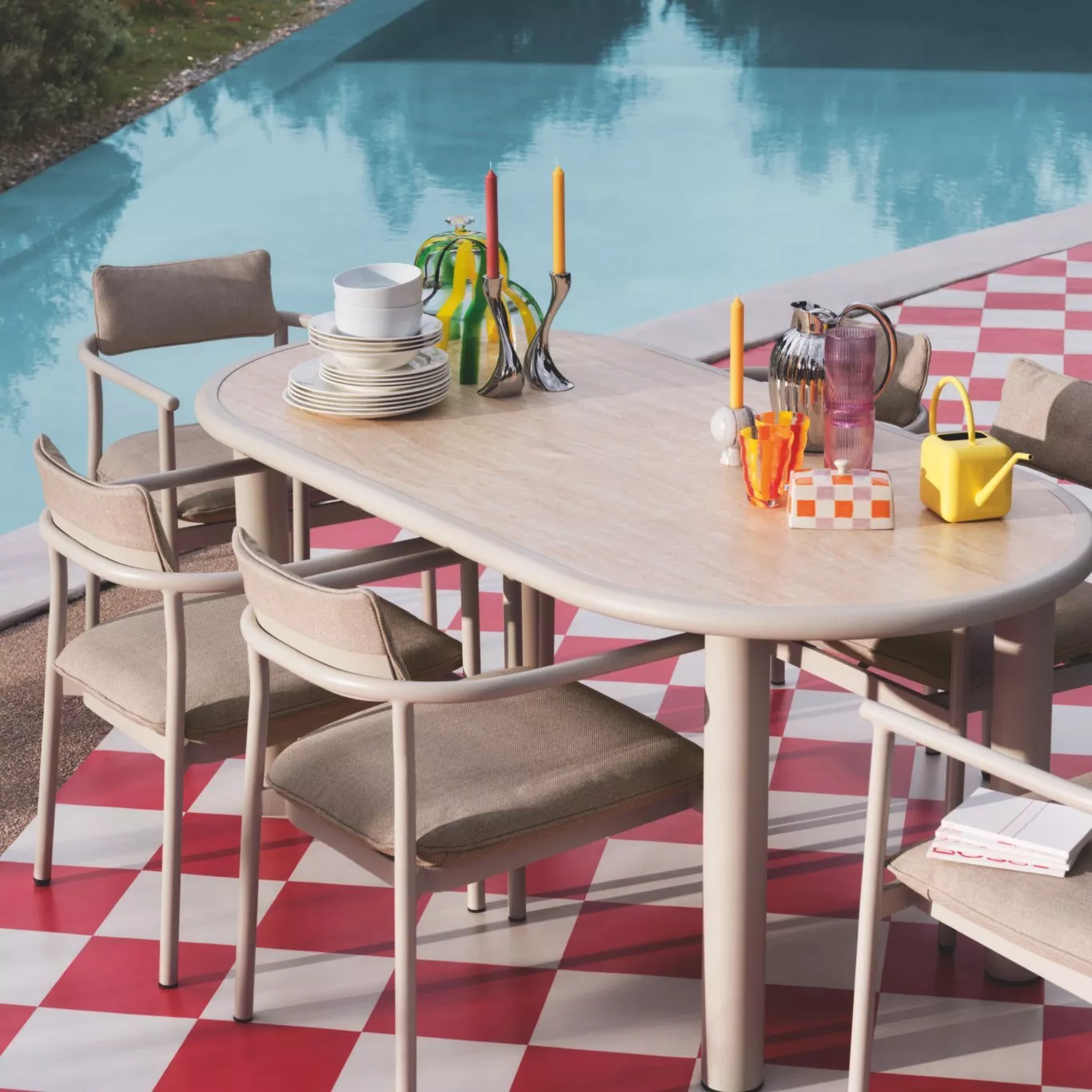 A beautifully arranged table with vibrant flowers, candles, ceramics, and glassware. Elegant and colourful setting.