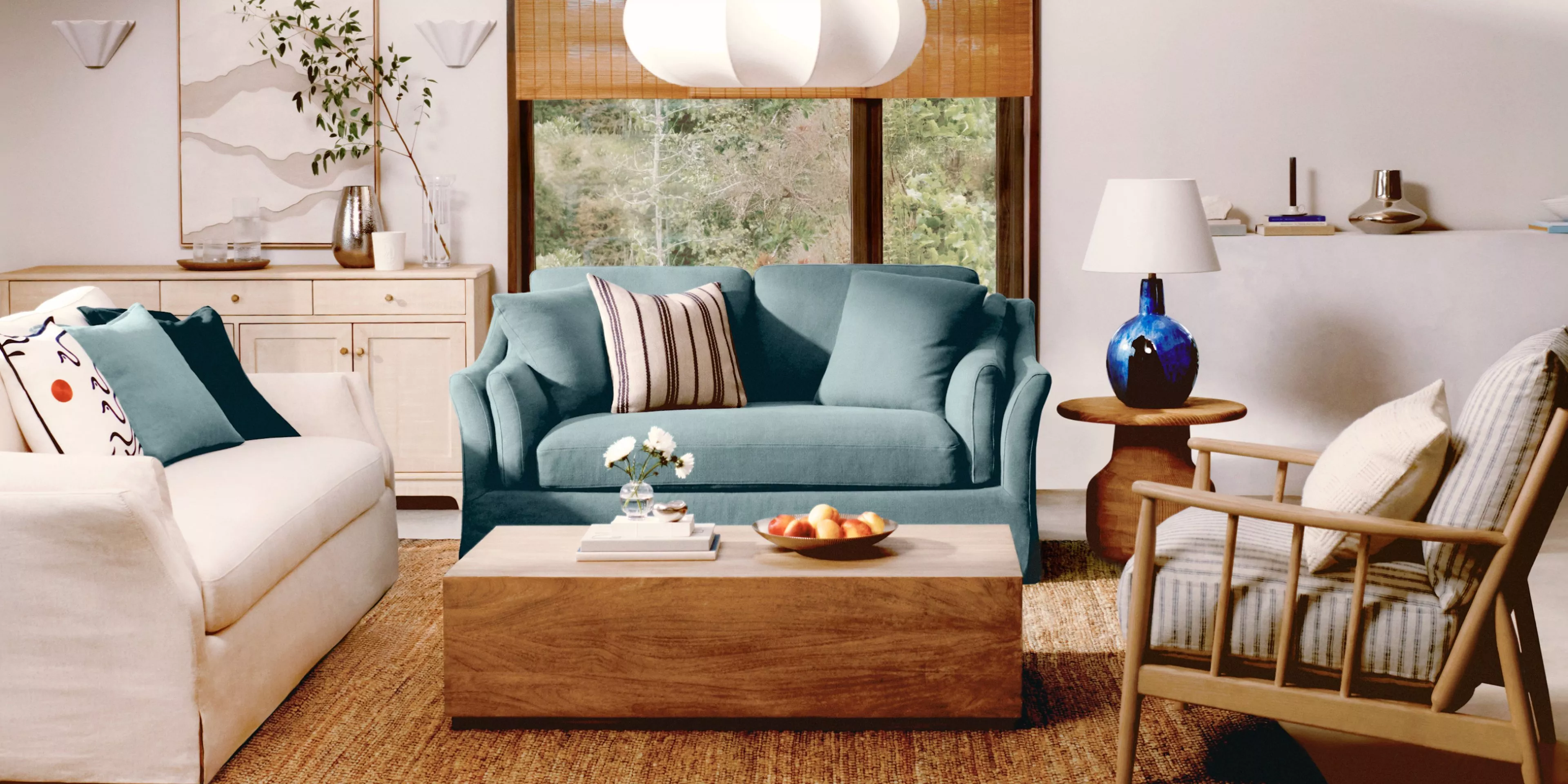 Cosy living room with teal and cream sofas, wooden coffee table, and stylish accents, including a blue lamp.