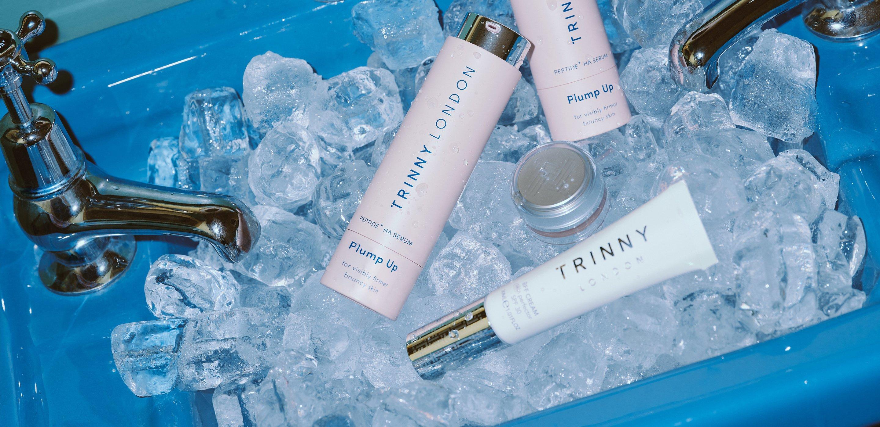 Trinny London Serums and SPF cream in blue sink full of ice cubes