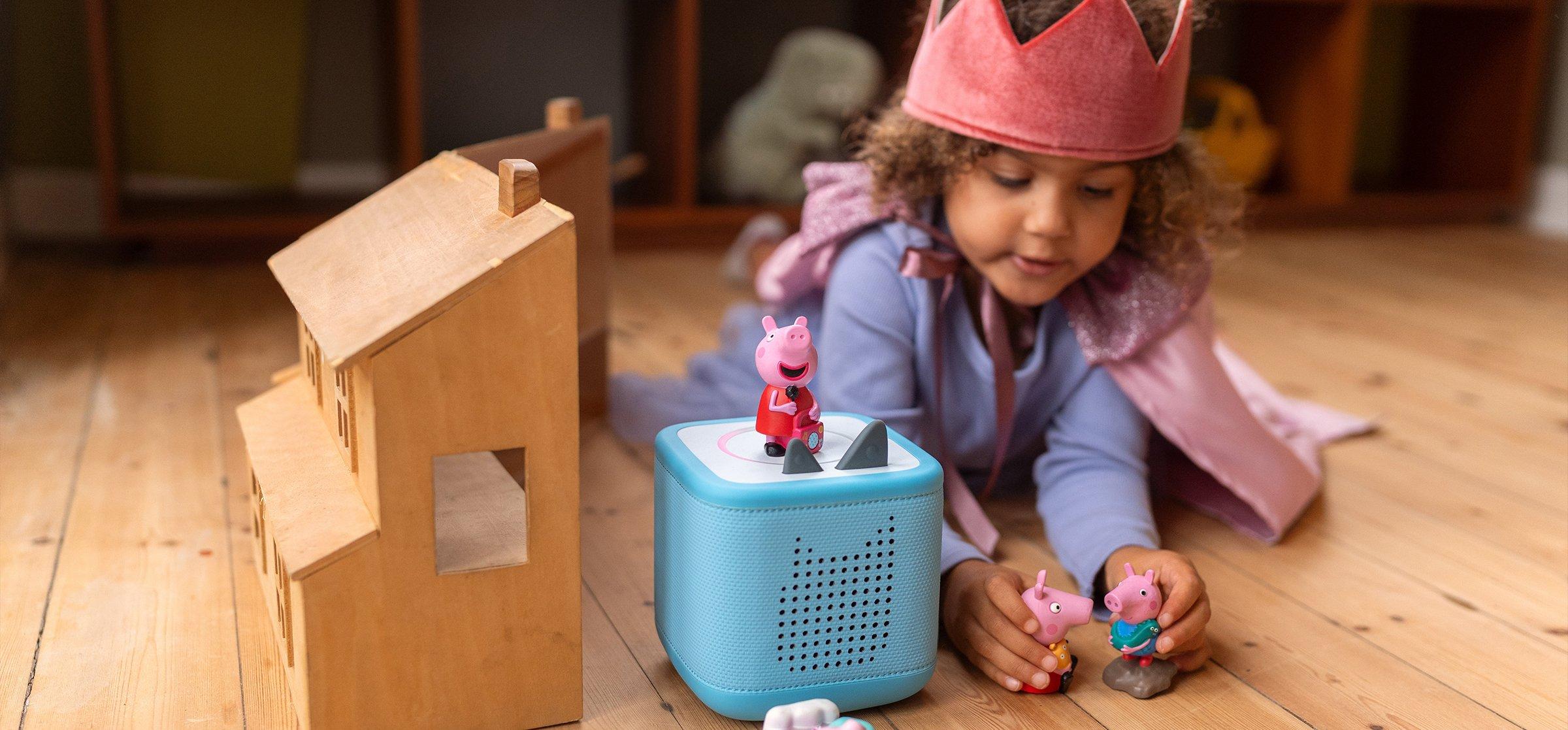 Toddler sat on the floor playing with toys next to a Toniebox 2