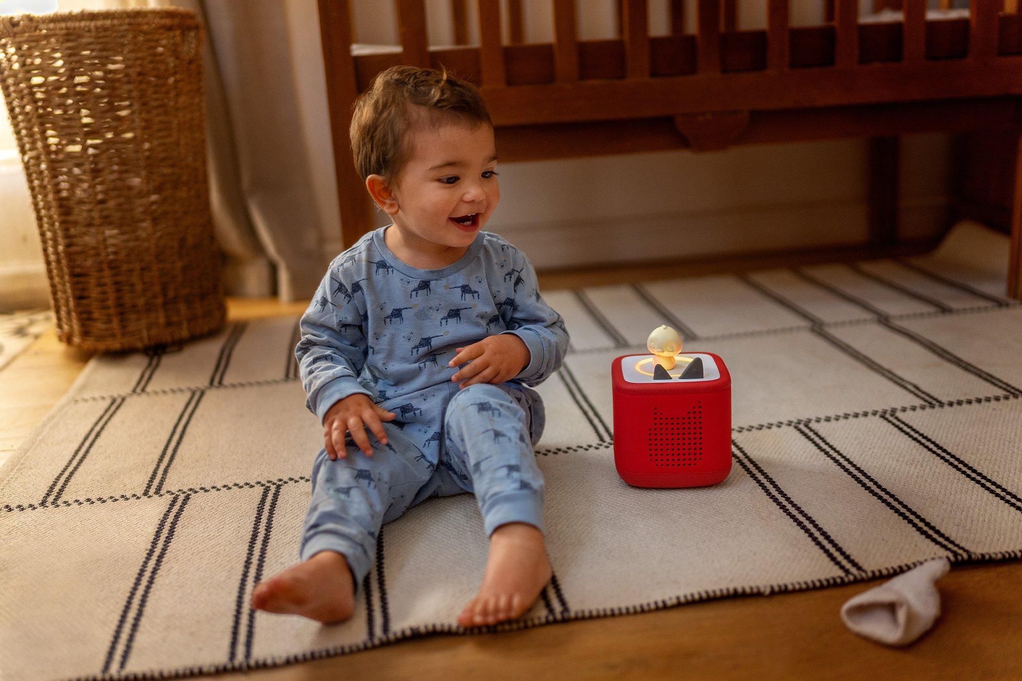 Toddler sat on the floor next to a Toniebox 2