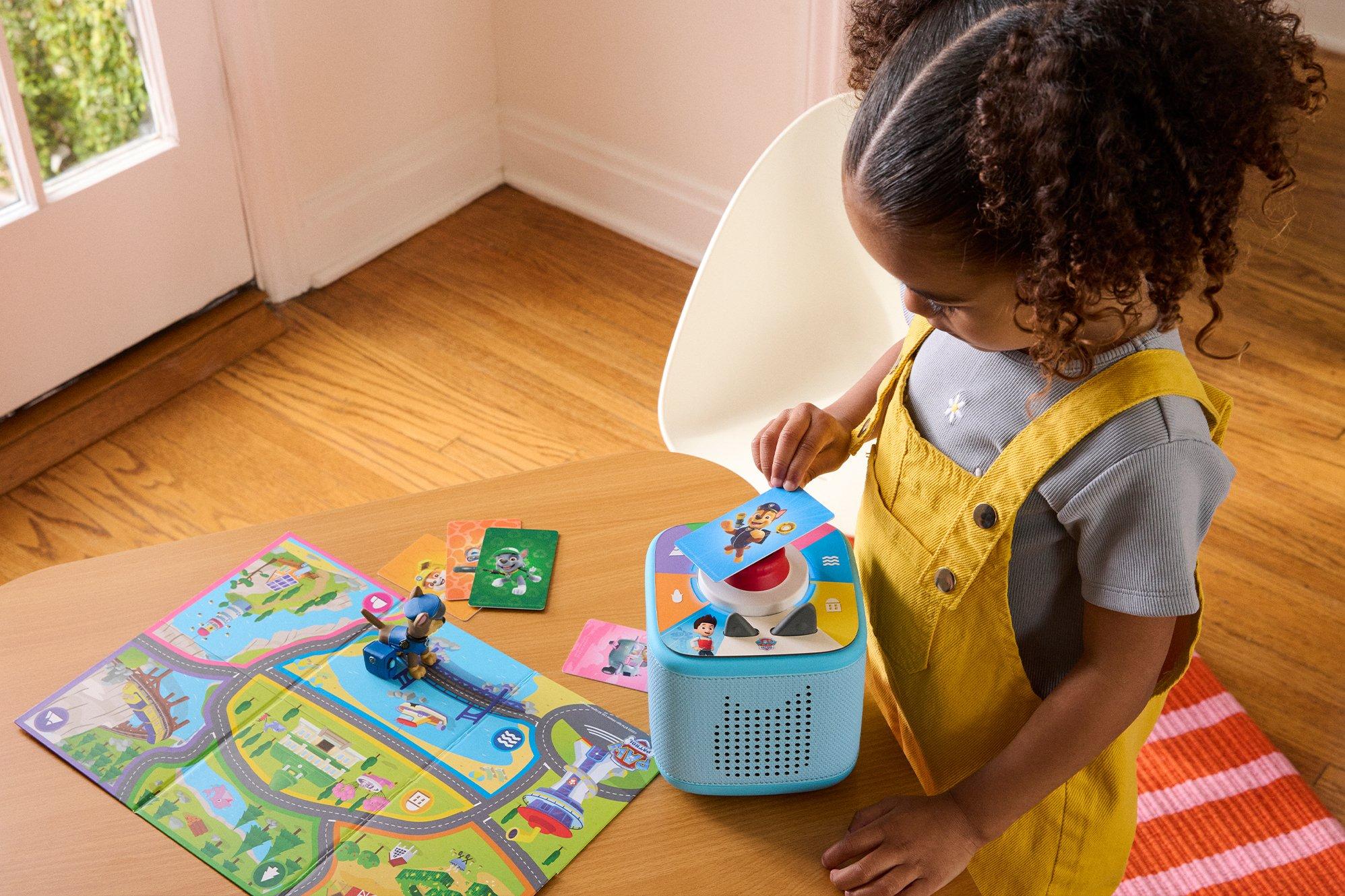 Toddler sat at a table playing with a Toniebox 2