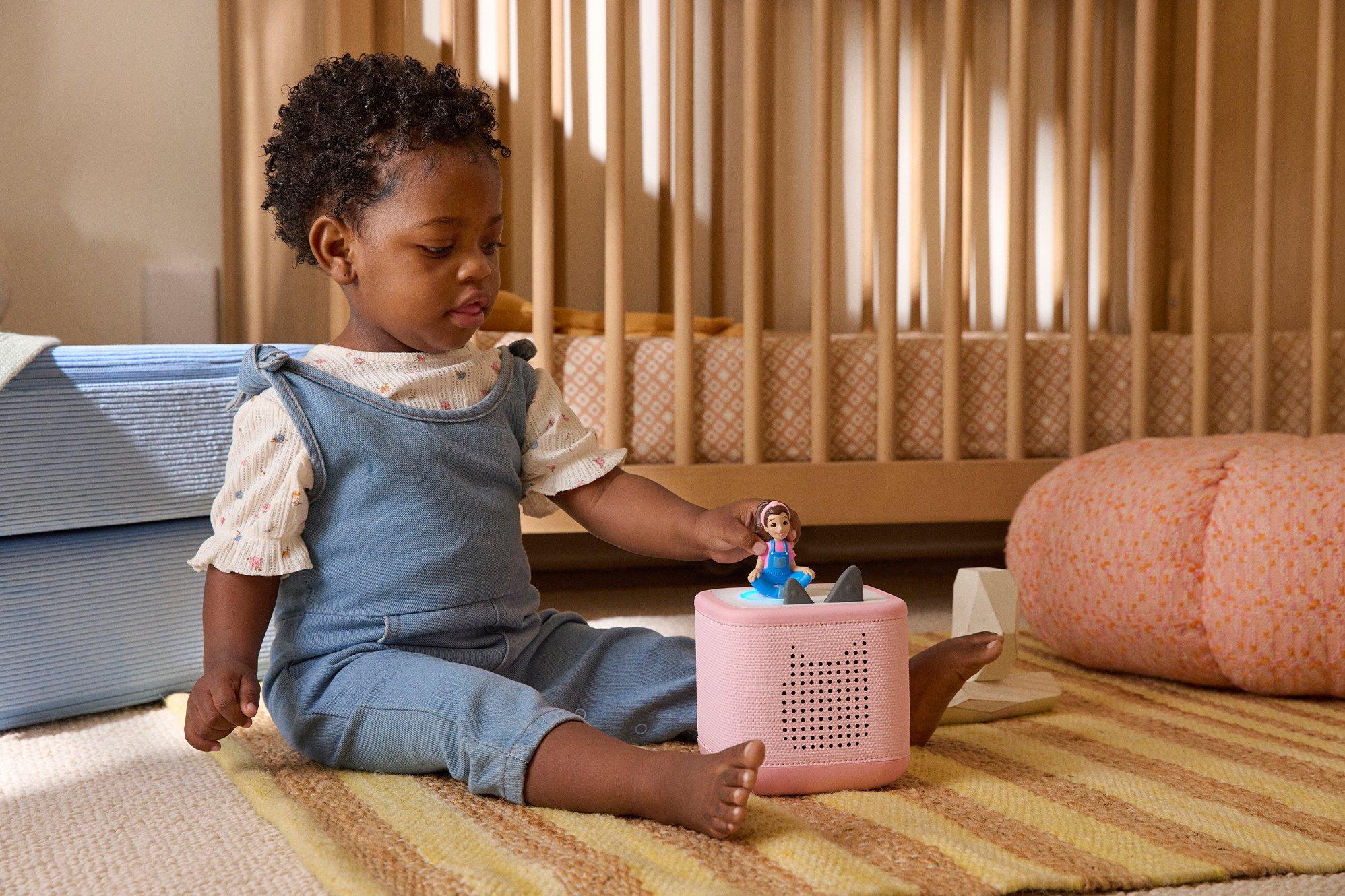 Toddler sat on the floor playing with a Toniebox 2