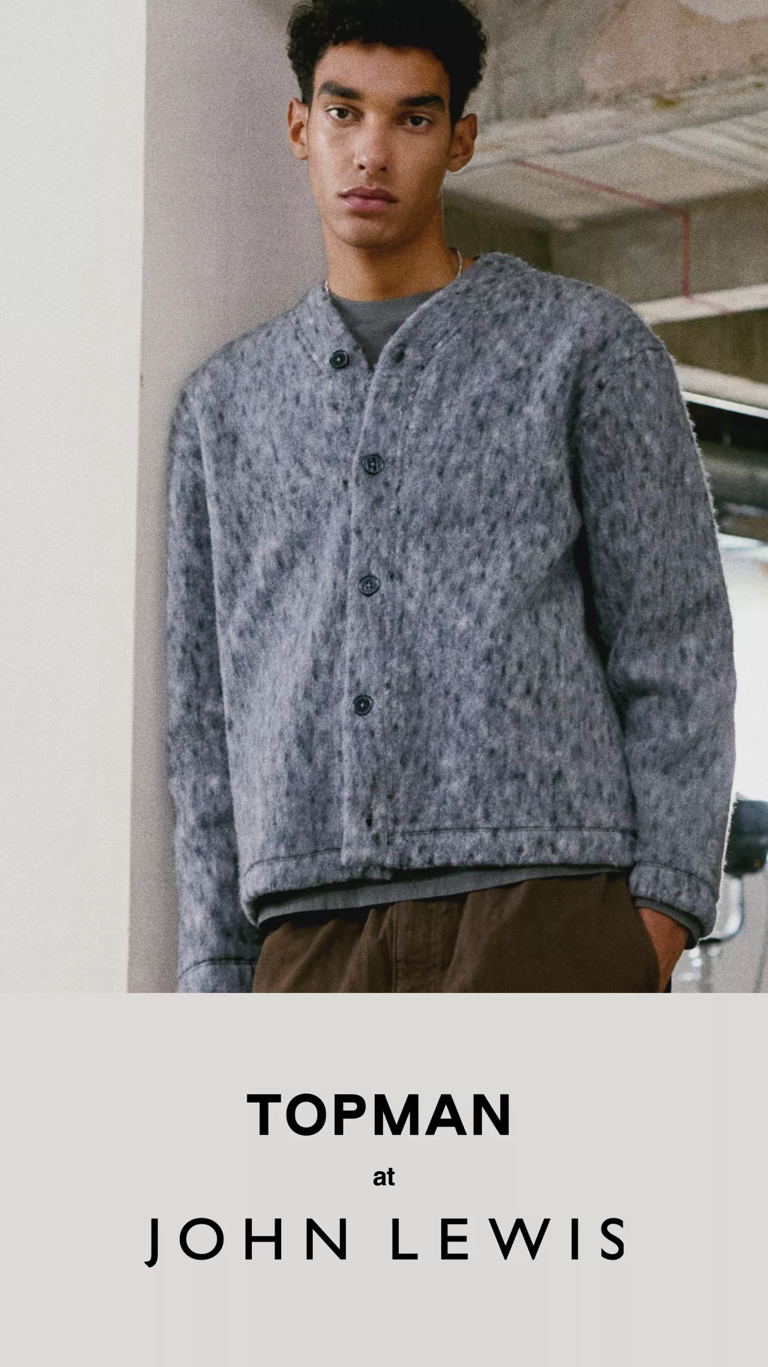 Male model wearing a grey button-up cardigan and brown trousers, Topman at John Lewis fashion advert.