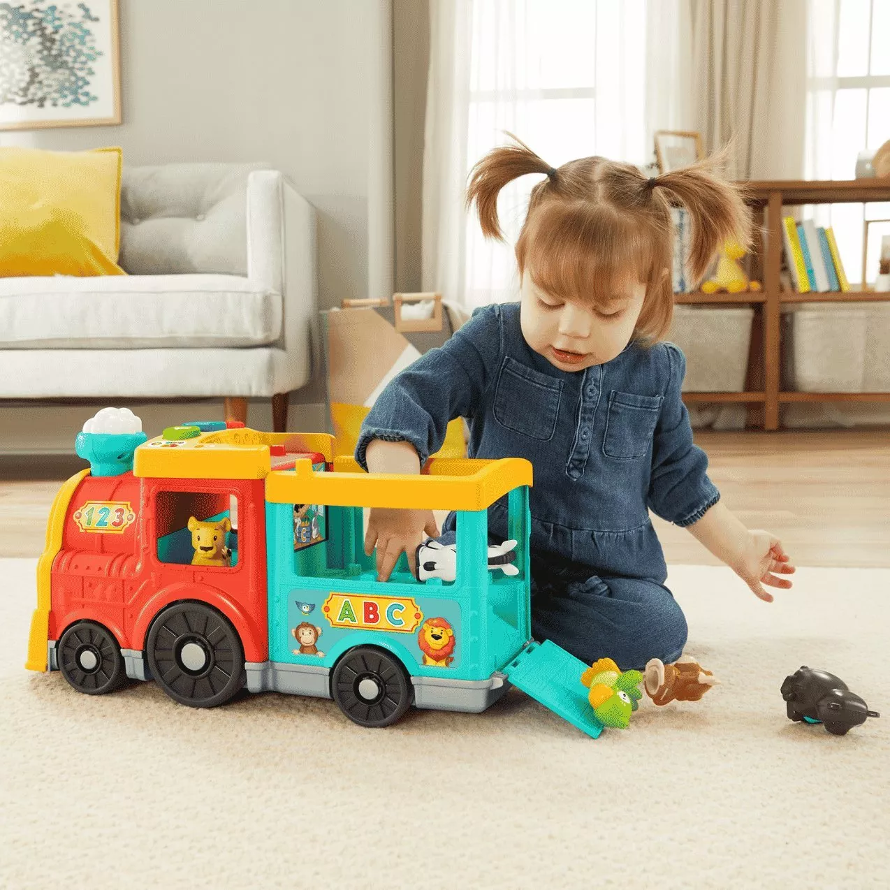 Toddler playing with colourful ABC animal toy bus on living room carpet, educational preschool activity at home