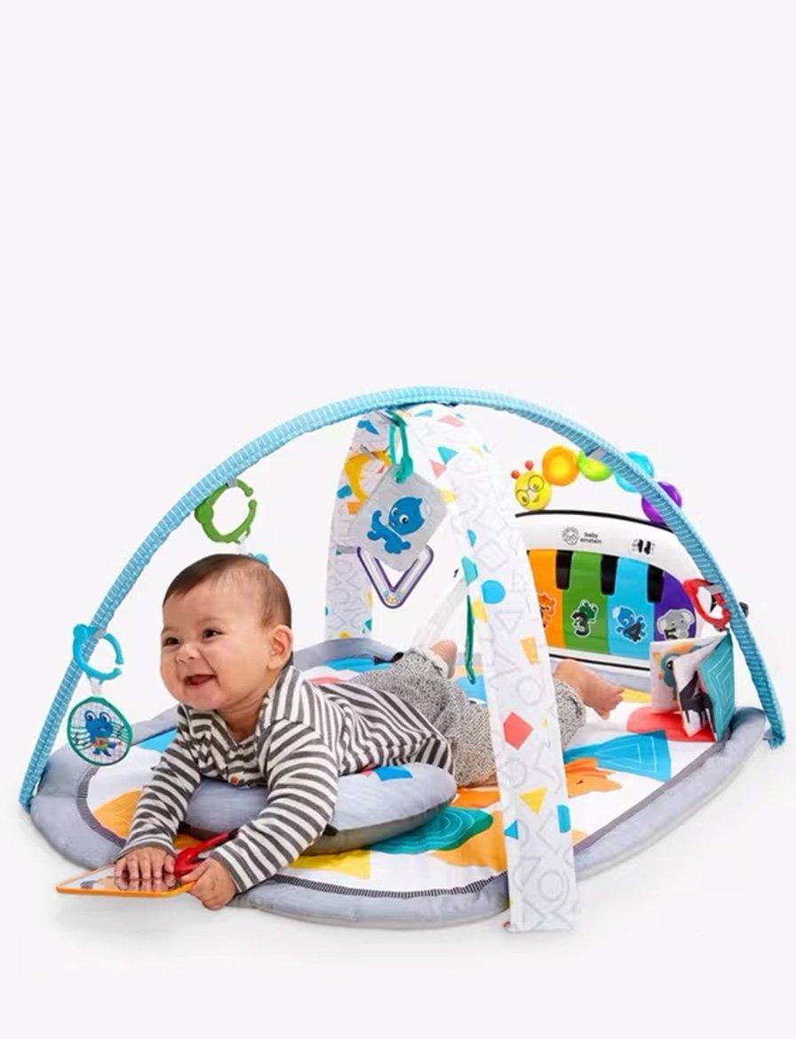 Smiling baby lying on a colorful play gym with hanging toys