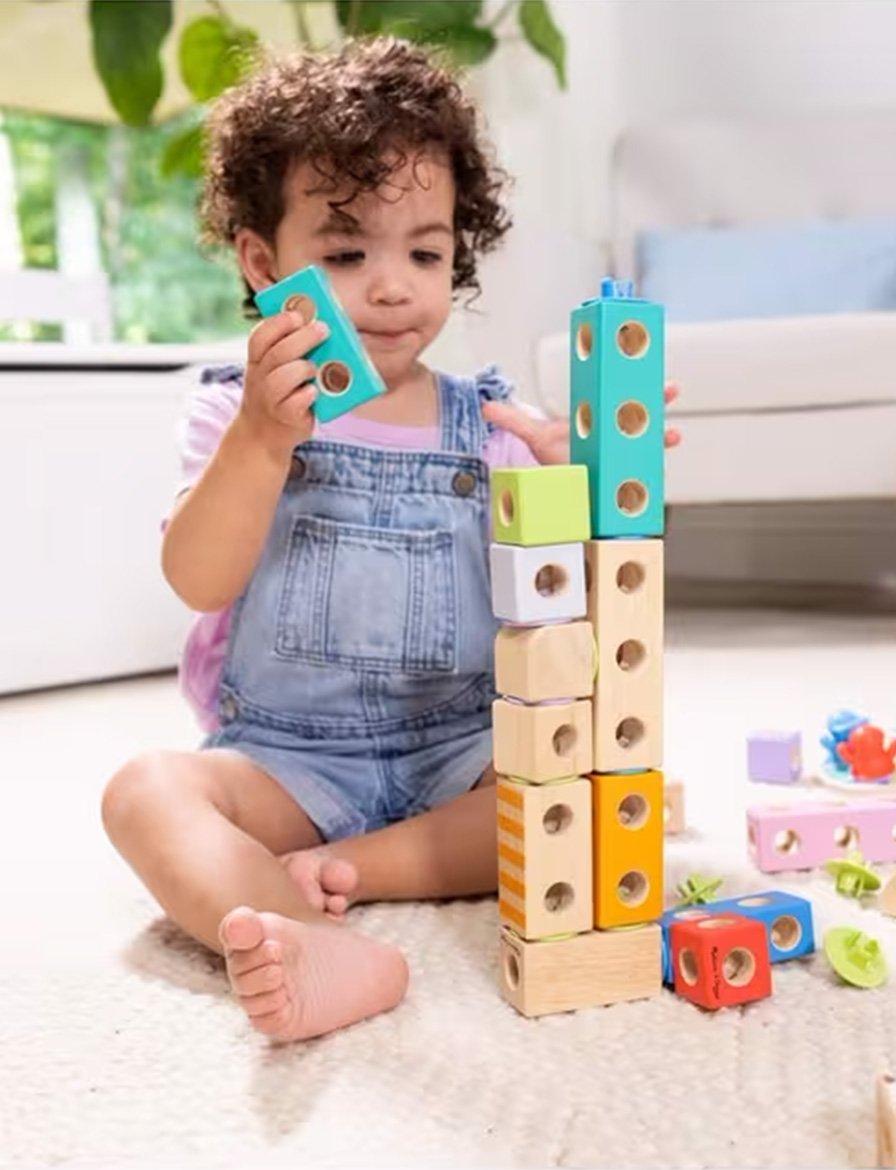 Toddler stacking colorful wooden blocks on the floor