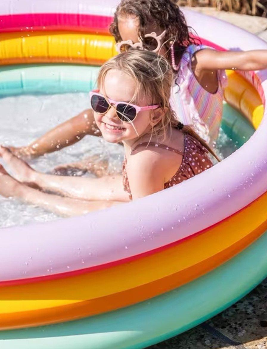 Two kids playing in a colorful inflatable pool.