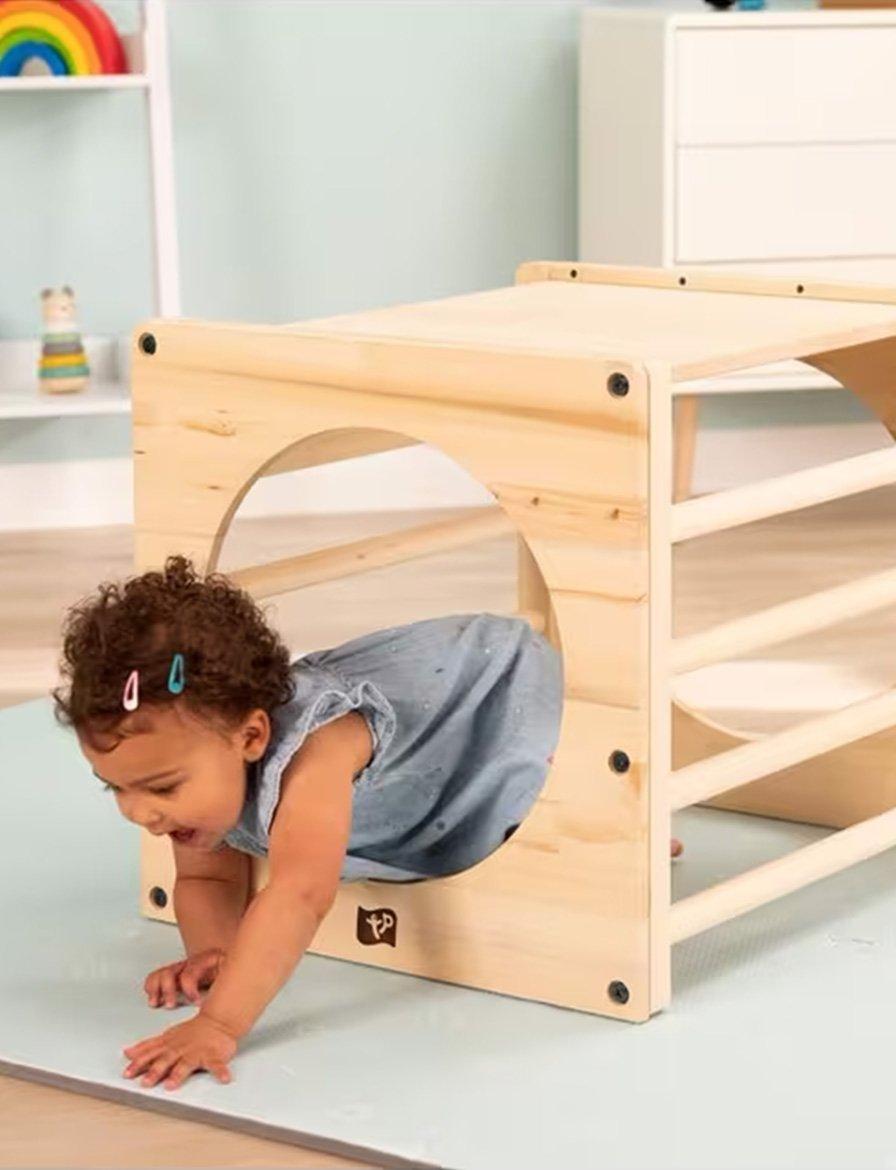 Toddler crawling through a wooden play tunnel