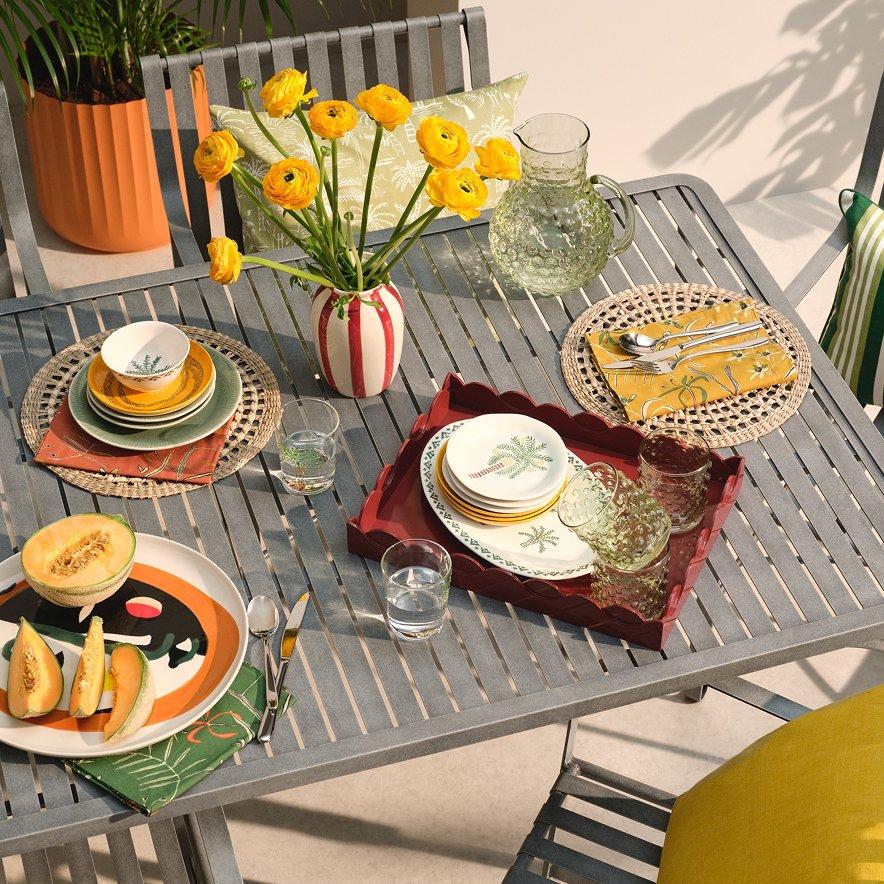 Garden table dressed with summery outdoor dining plates and cups