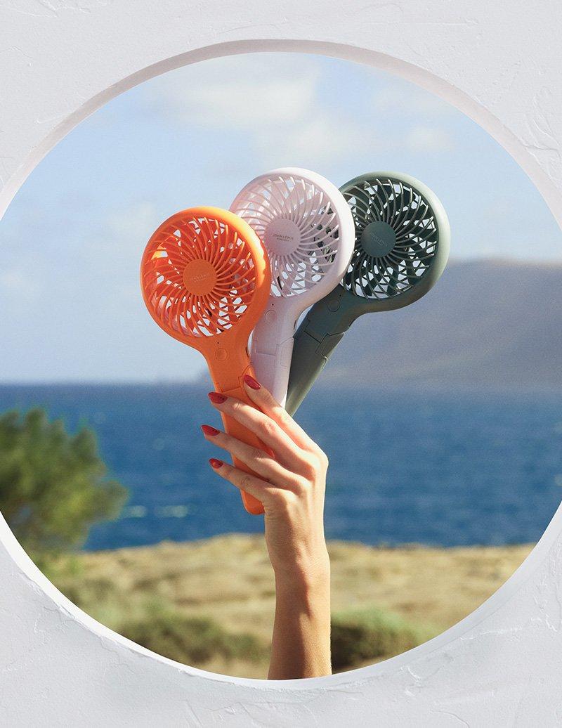 Hand holding up three battery powered travel fans
