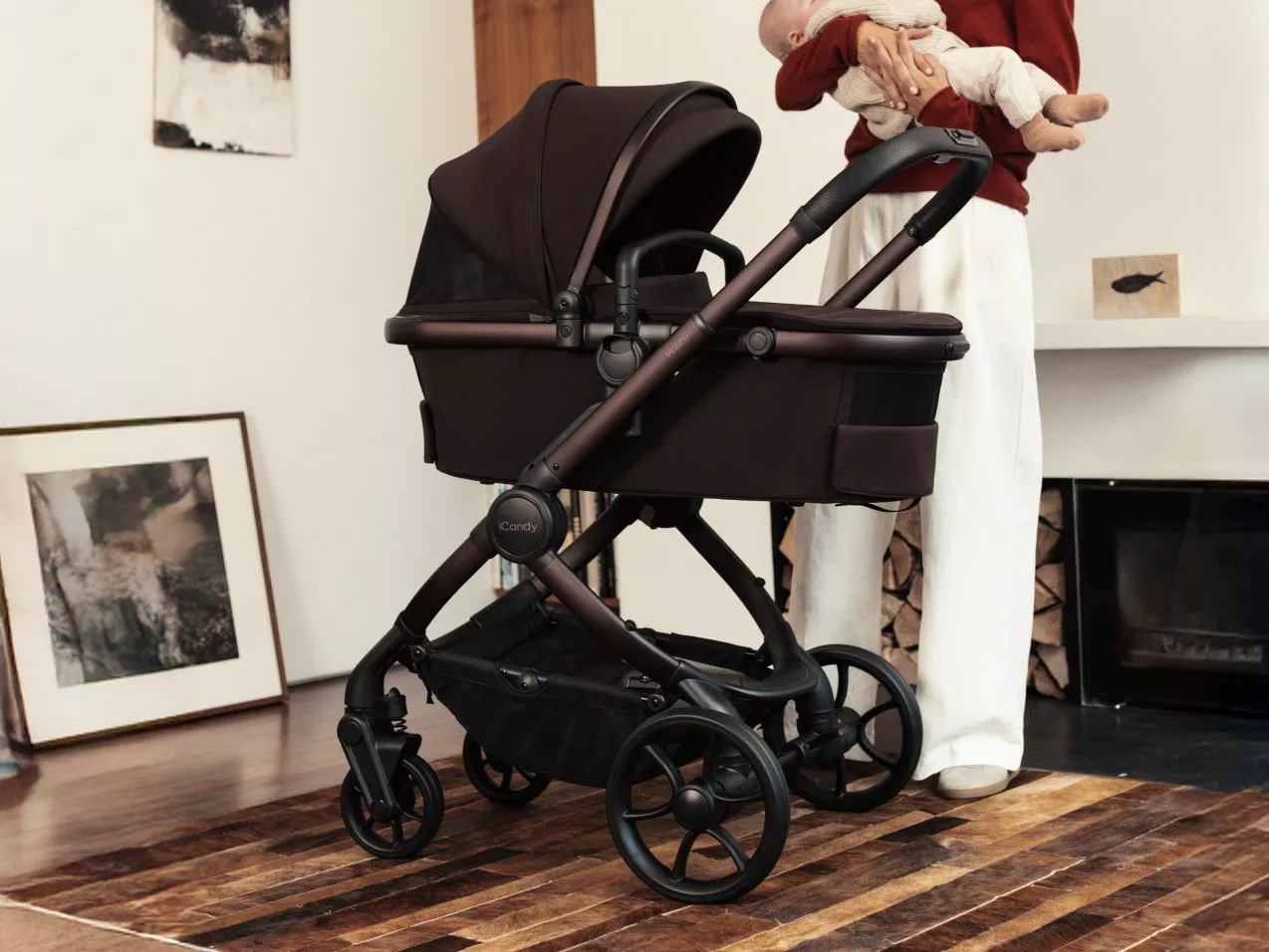Modern black baby pram pushchair in stylish home interior, parent holding newborn beside stroller indoors