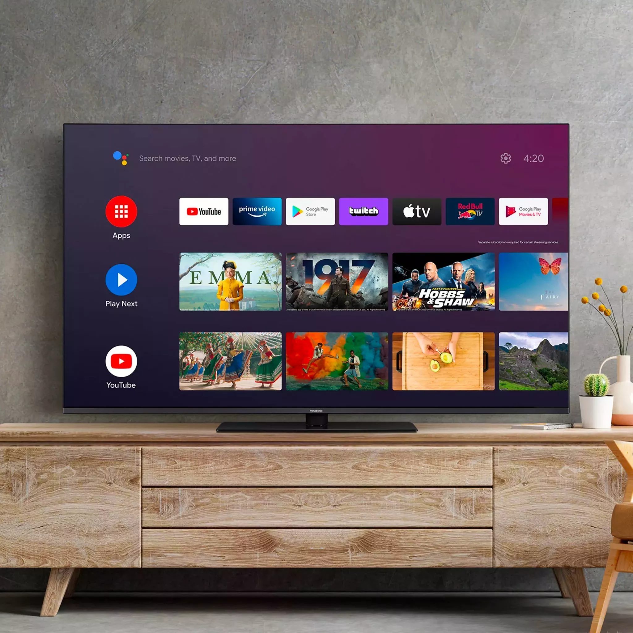 A smart TV displaying the Android TV home screen with apps and content, placed on a light wood media console.