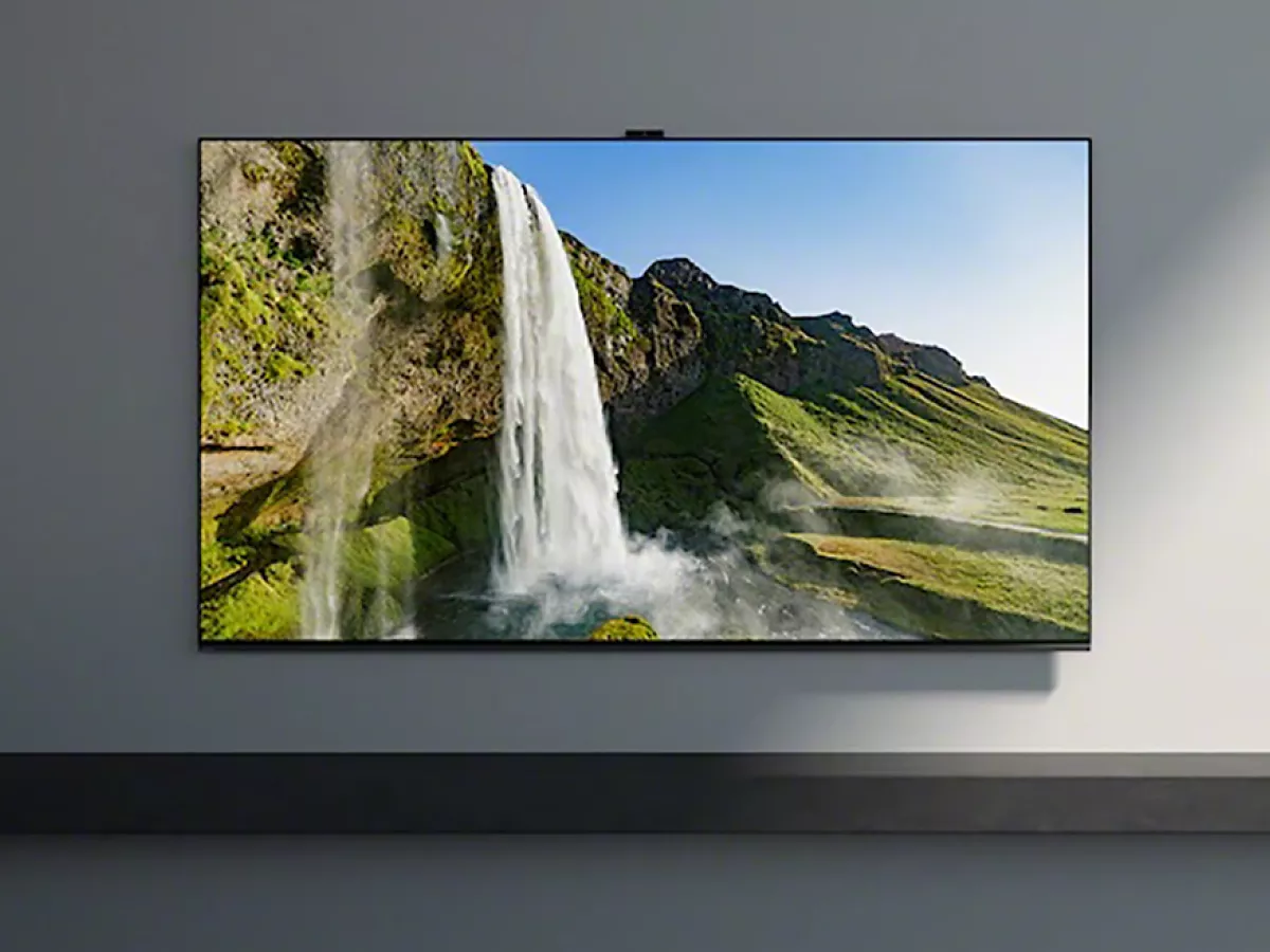 Wall-mounted flat-screen smart TV displaying a scenic waterfall and mountain landscape in a modern living room setting