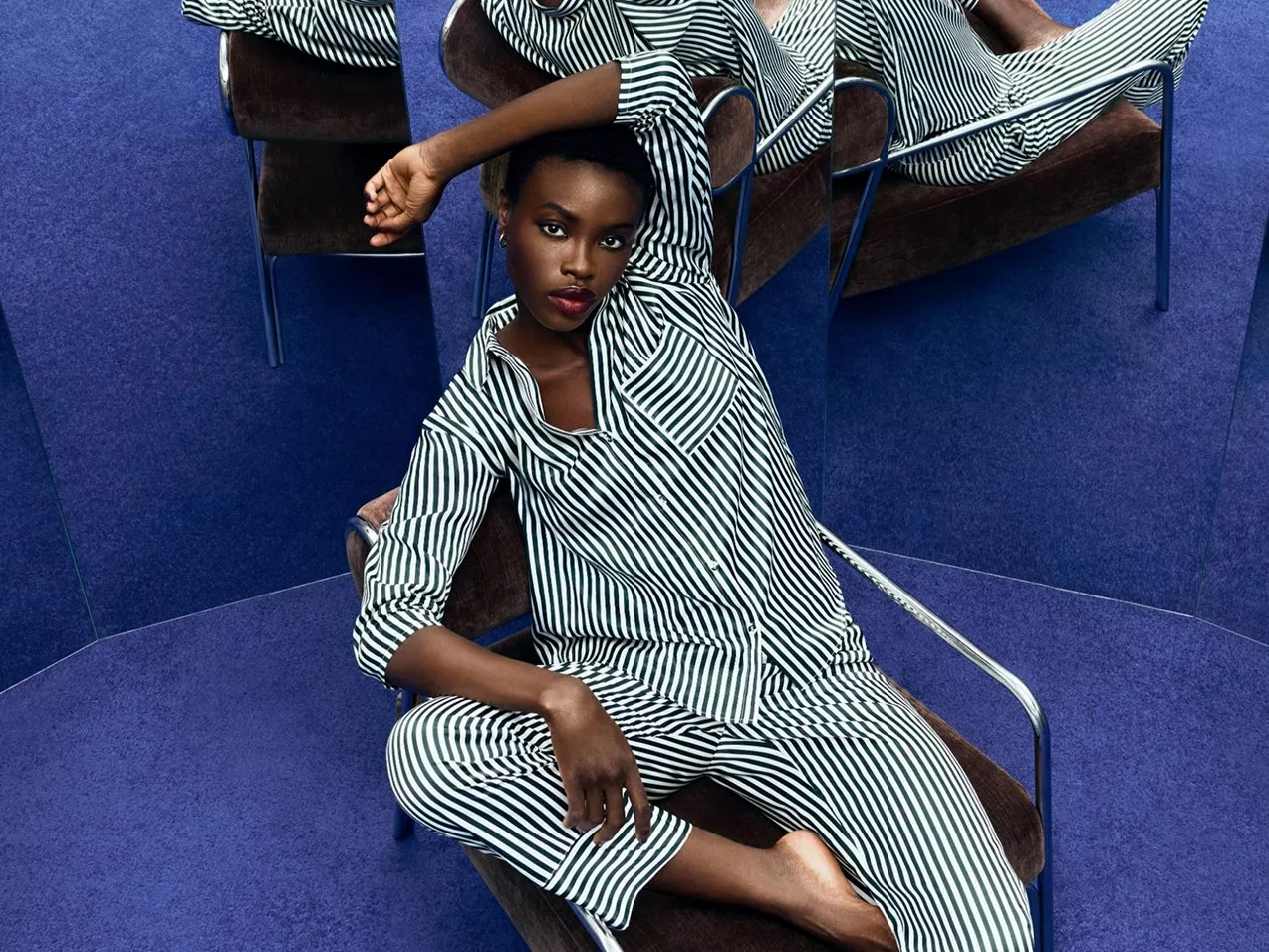 woman dressed in green in striped pyjamas sitting in chair against lots of mirrors