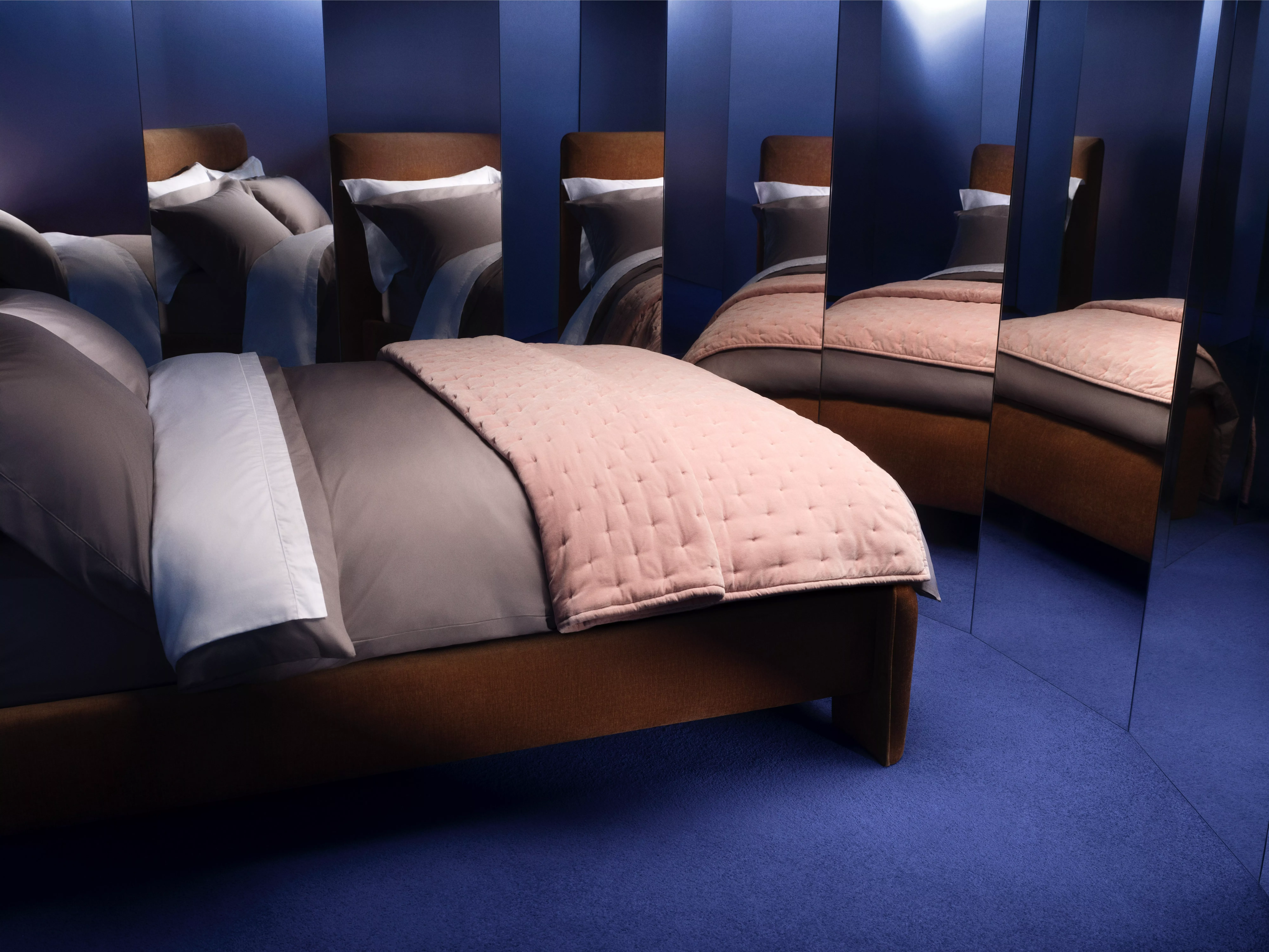 A contemporary bedroom interior with a warm wood bed frame and layered bedding.