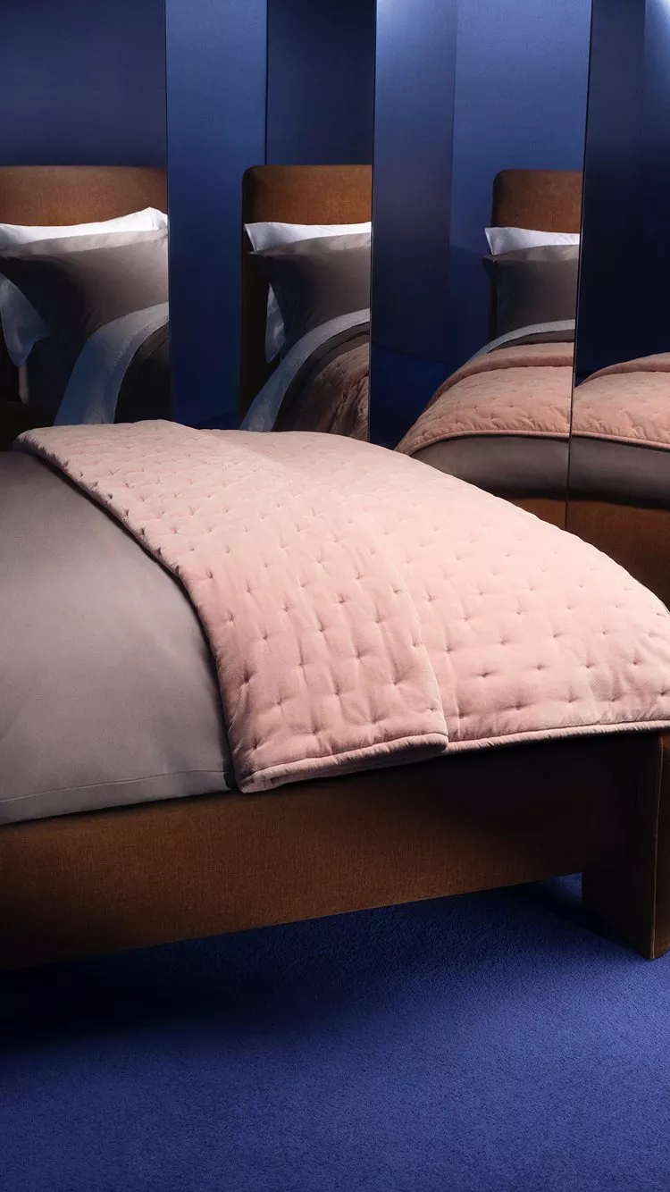 Bed with bedding and pillow, next to lots of mirrors