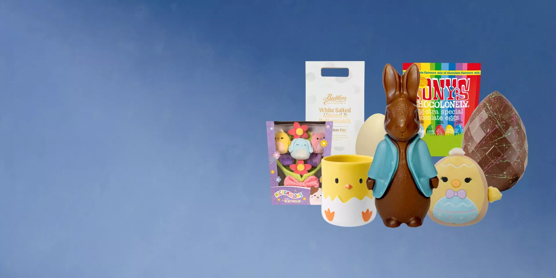 Playful rabbit-themed decor on a blue surface, featuring a bunny lamp, basket, toy rabbits, and a floral wreath.