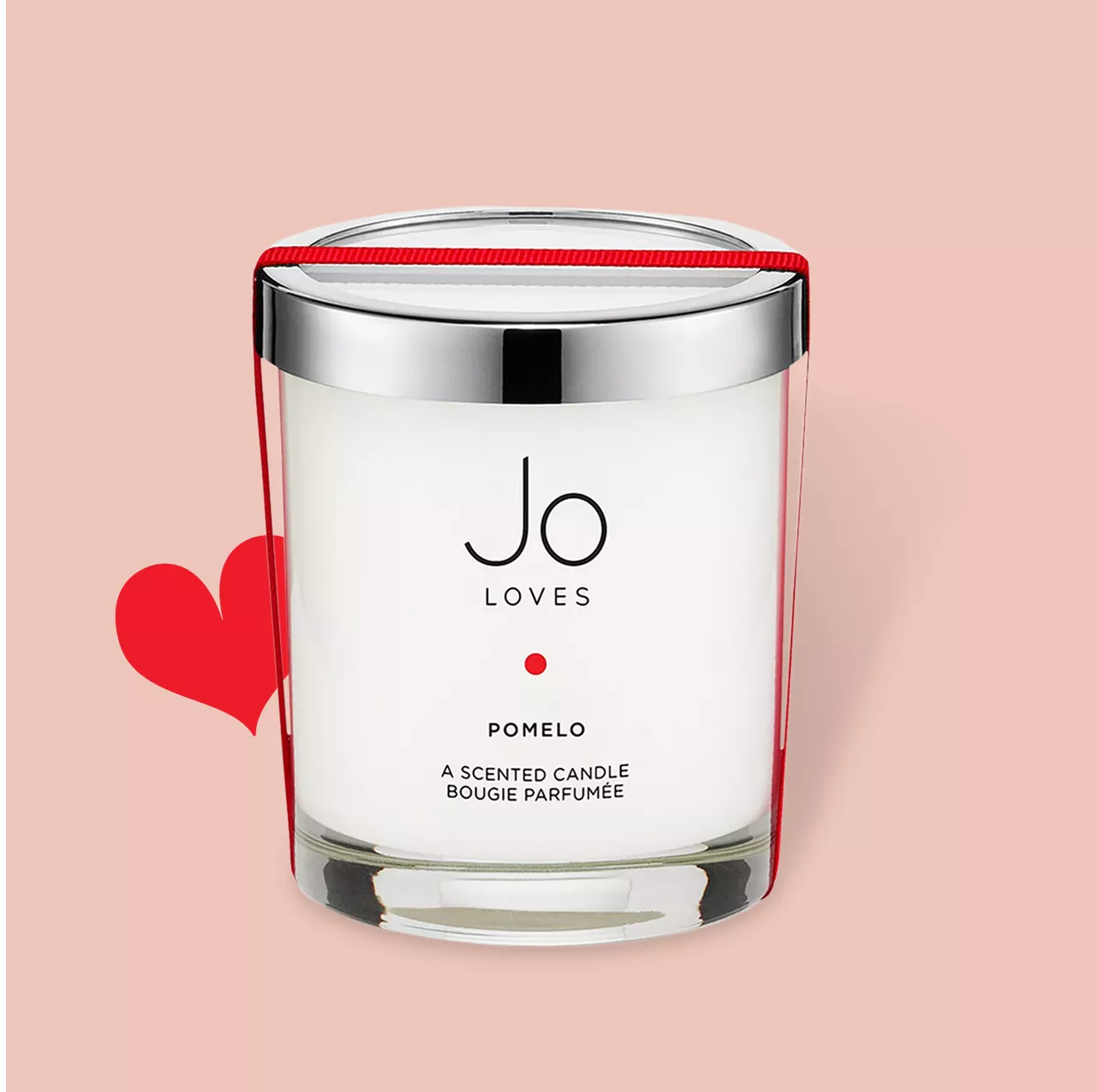 A Jo Loves Pomelo scented candle with a silver lid, set against a pink background with a red heart.