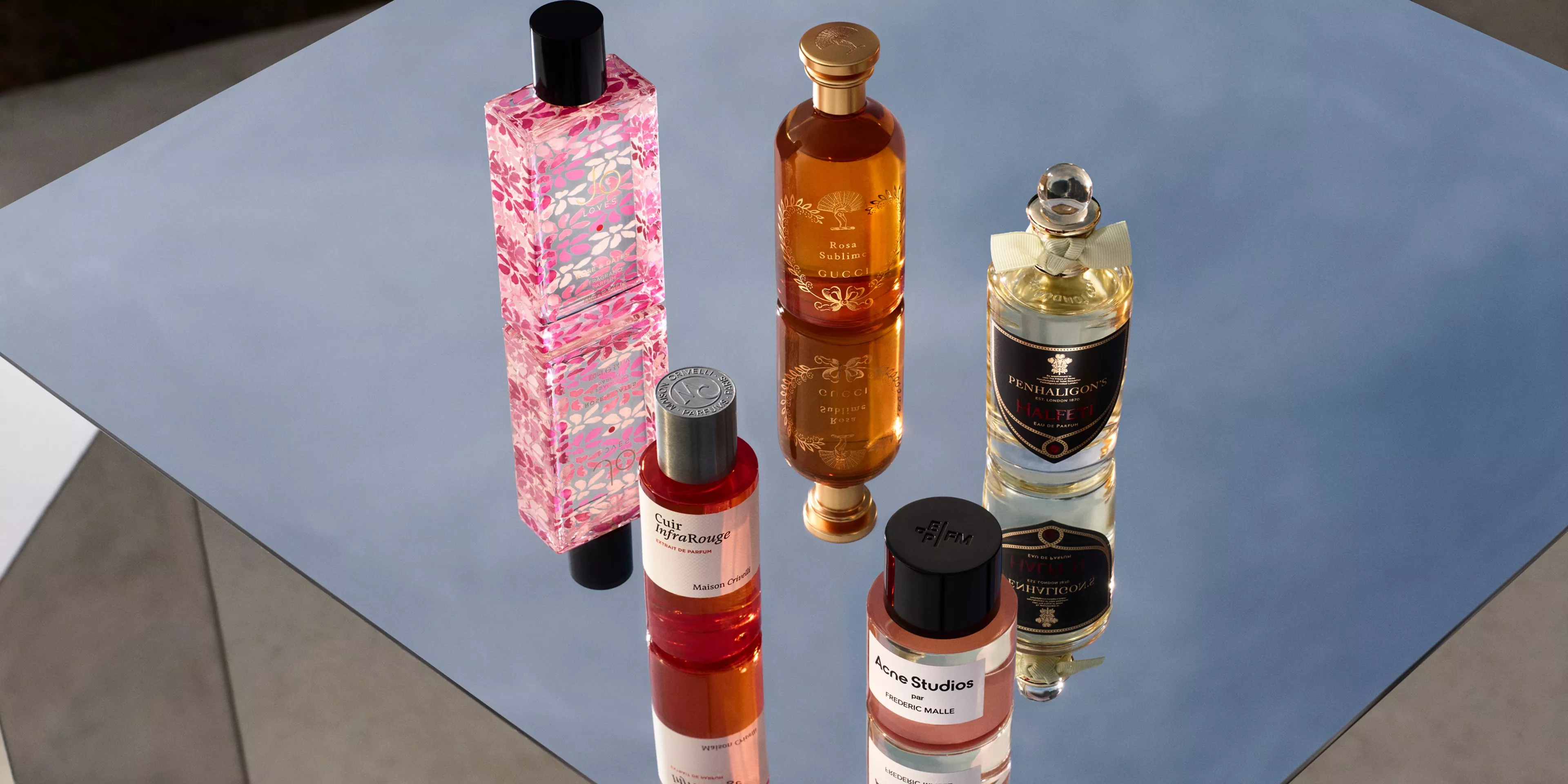 Perfume bottles elegantly arranged on a reflective surface, showcasing various luxurious fragrances.
