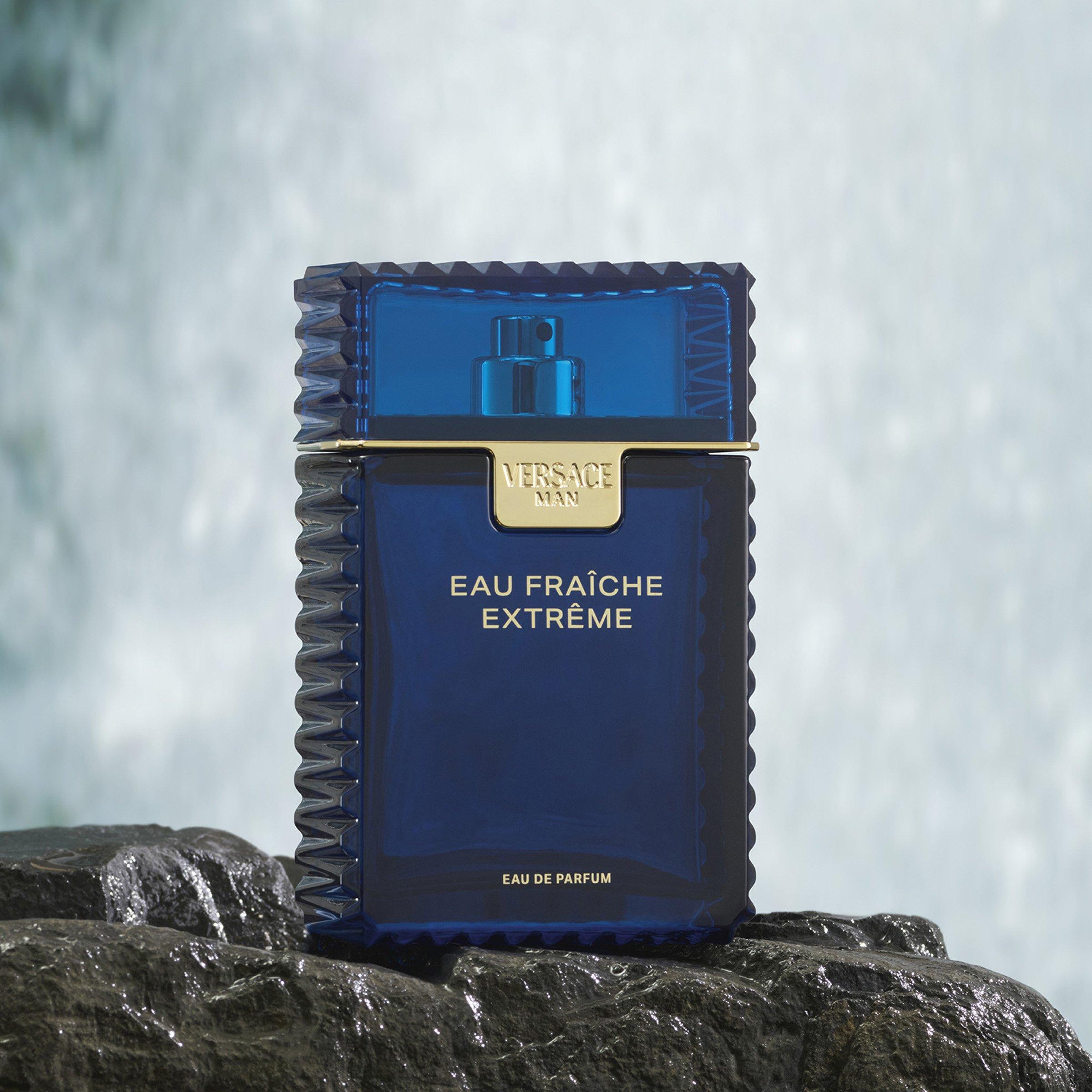 bottle of Versace fraiche sitting on a rock with a waterfall behind it