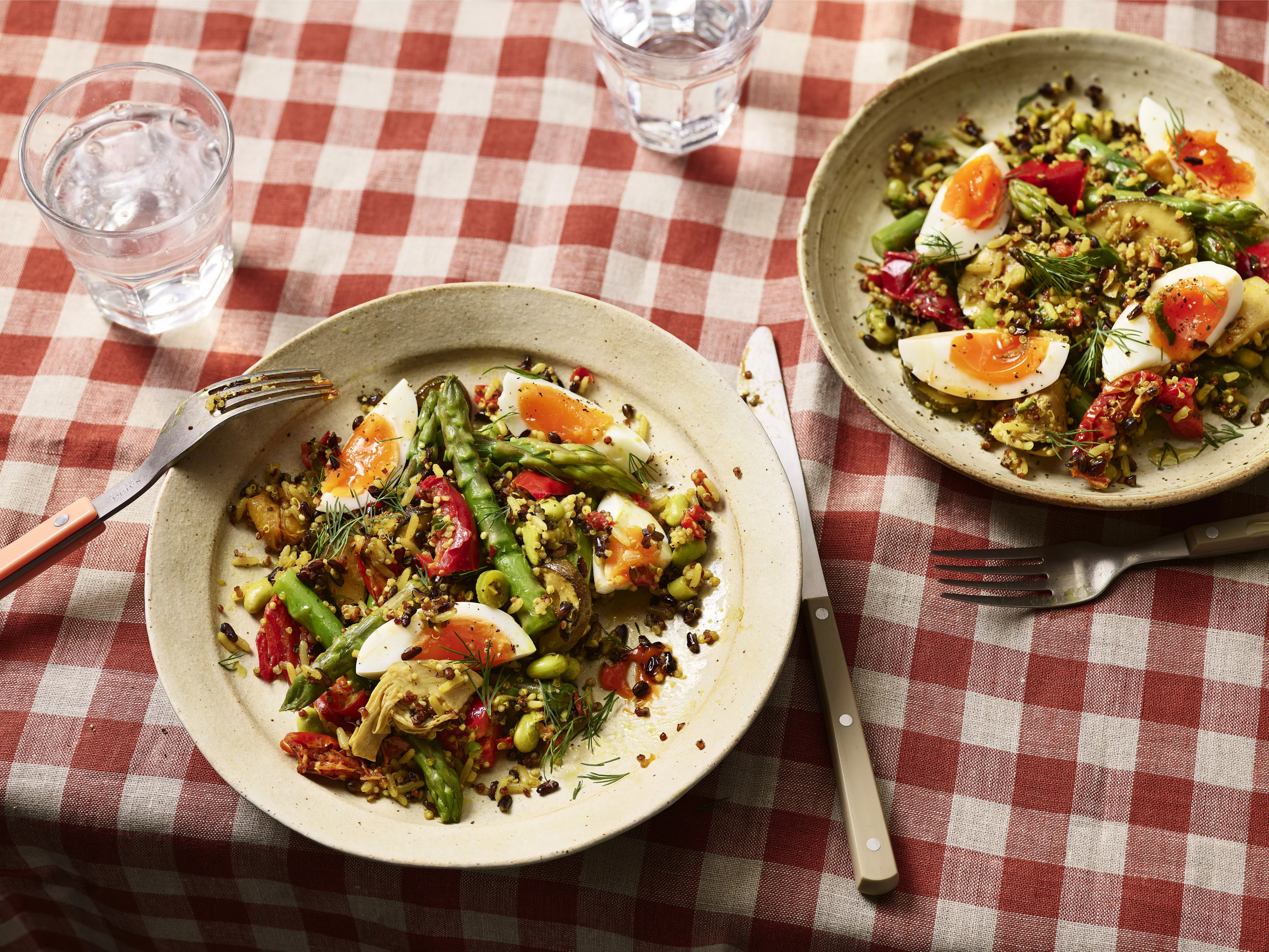 Spring asparagus and quinoa salad with soft-boiled eggs, tomatoes and herbs on a red gingham tablecloth