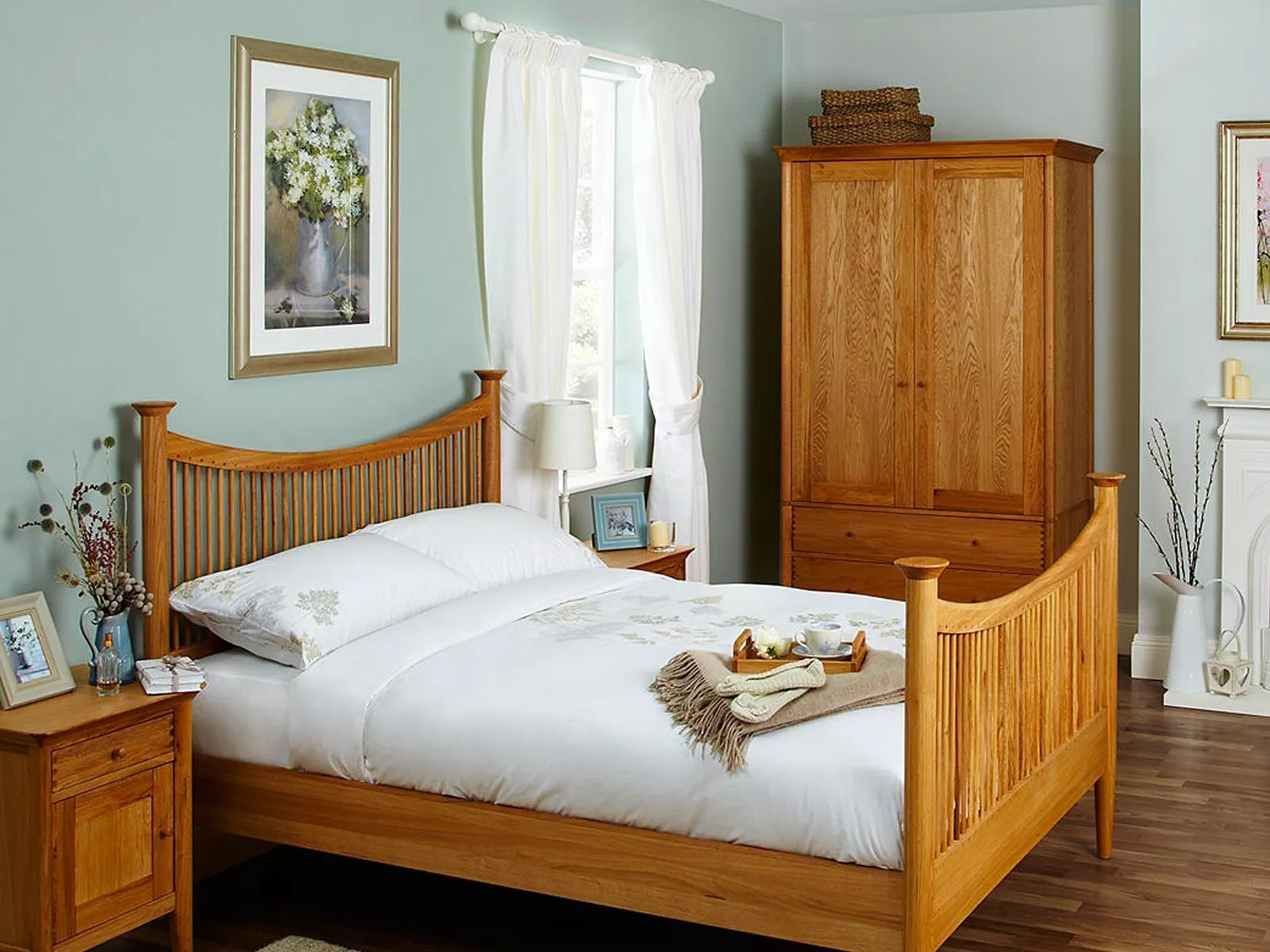 Cosy bedroom with wooden bed, matching wardrobe, and bedside table. Soft green walls and decorative accents.